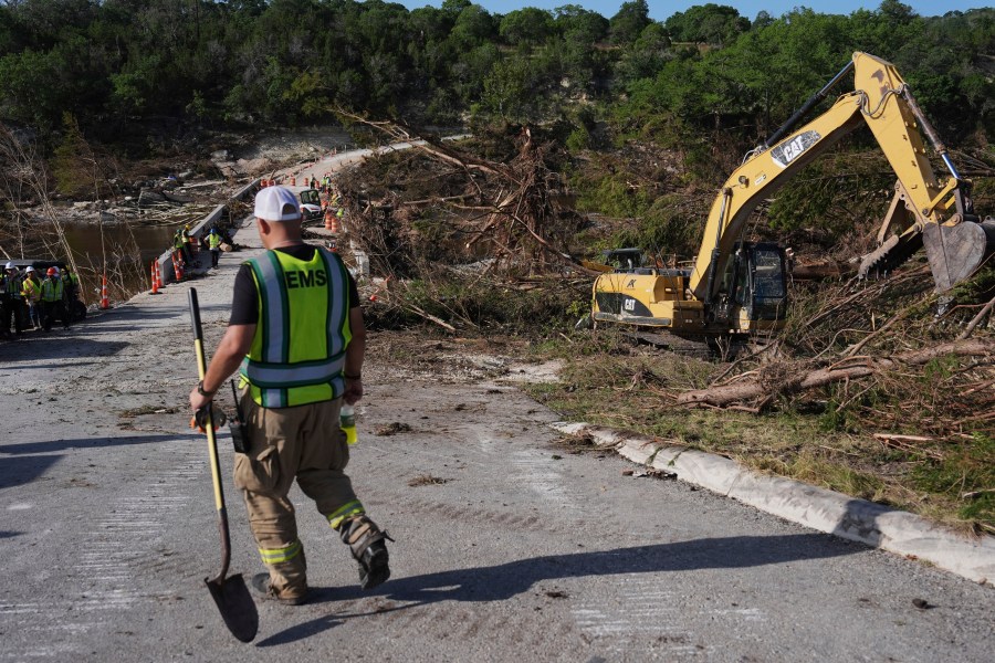 Crews work on the Cade Loop Bridge to clear debris following flooding, Thursday, July 10, 2025, in Ingram, Texas. (AP Photo/Joshua A. Bickel)