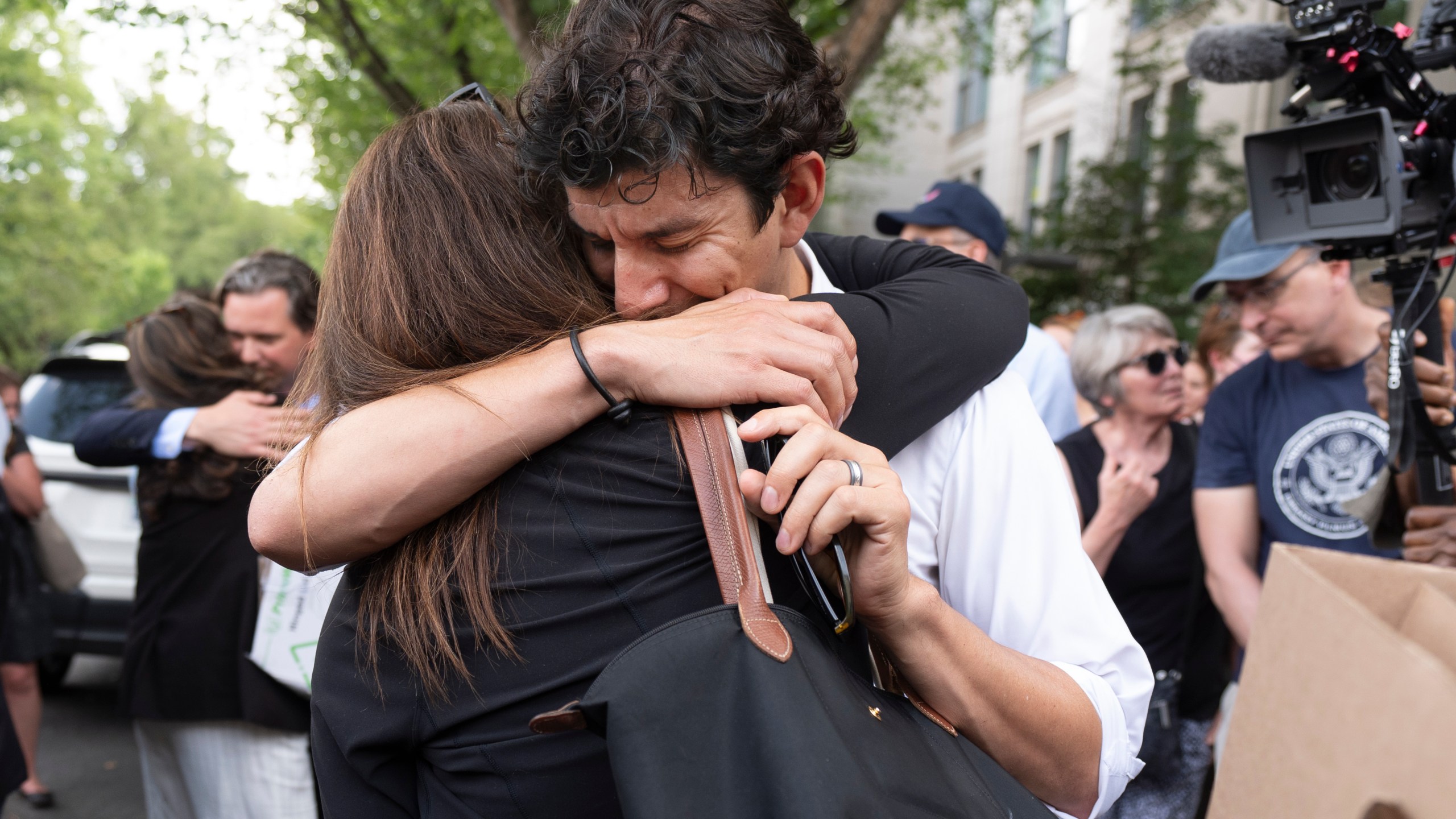 A fired State Department employee, left, is greeted outside of the Harry S. Truman Building, the headquarters of the State Department, in Washington, Friday, July 11, 2025. (AP Photo/Manuel Balce Ceneta)