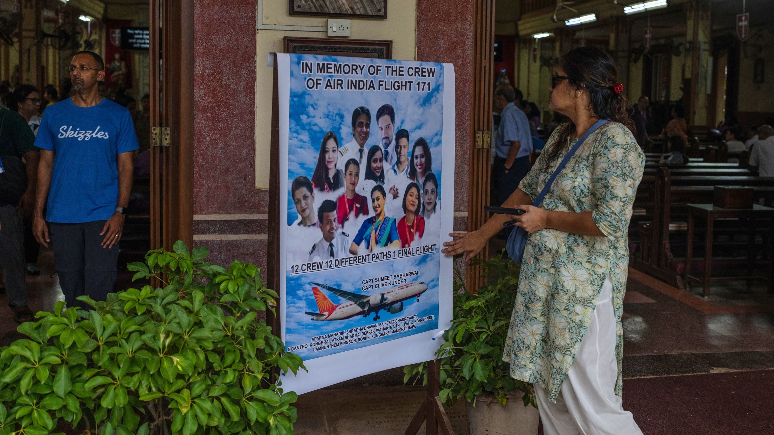 A woman offers tribute to the crew members of the Air India flight that crashed in Ahmedabad last month during a prayer meeting at a church in Mumbai, India, Saturday, July 12, 2025. (AP Photo/ Rafiq Maqbool)