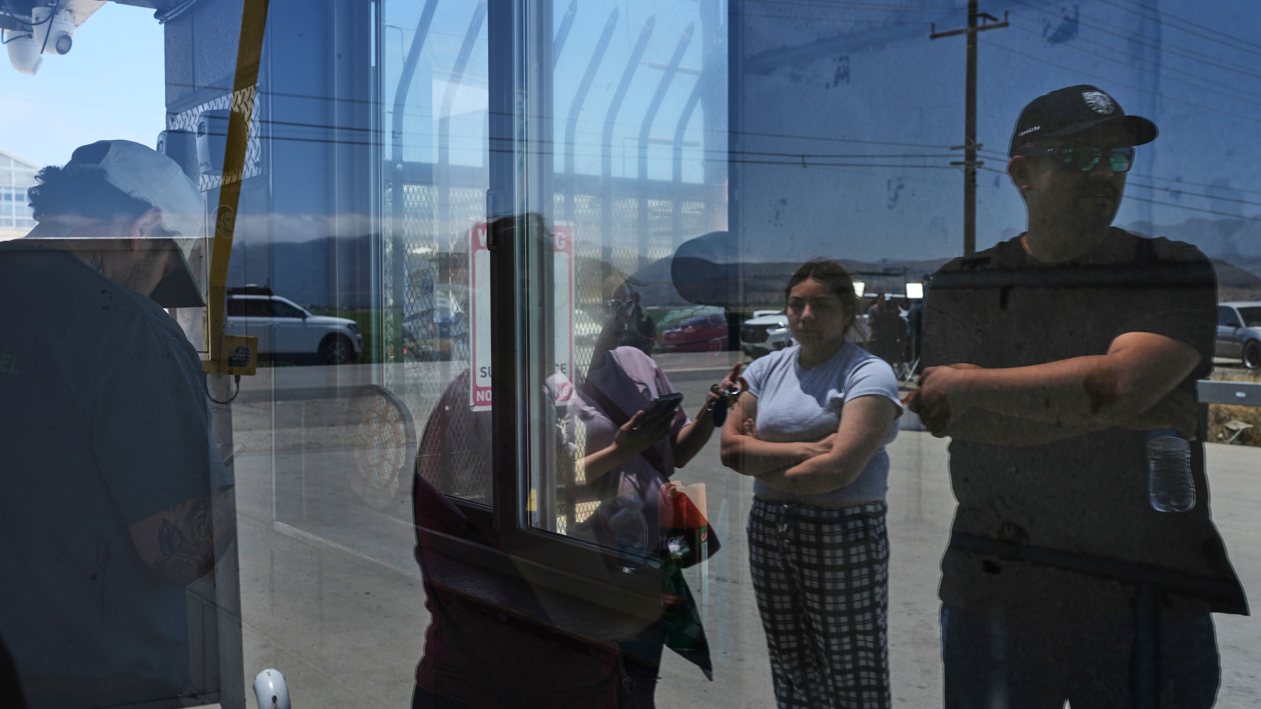 People wait outside of Glass House Farms, a day after an immigration raid on the facility, Friday, July 11, 2025, in Camarillo, Calif. (AP Photo/Jae C. Hong)