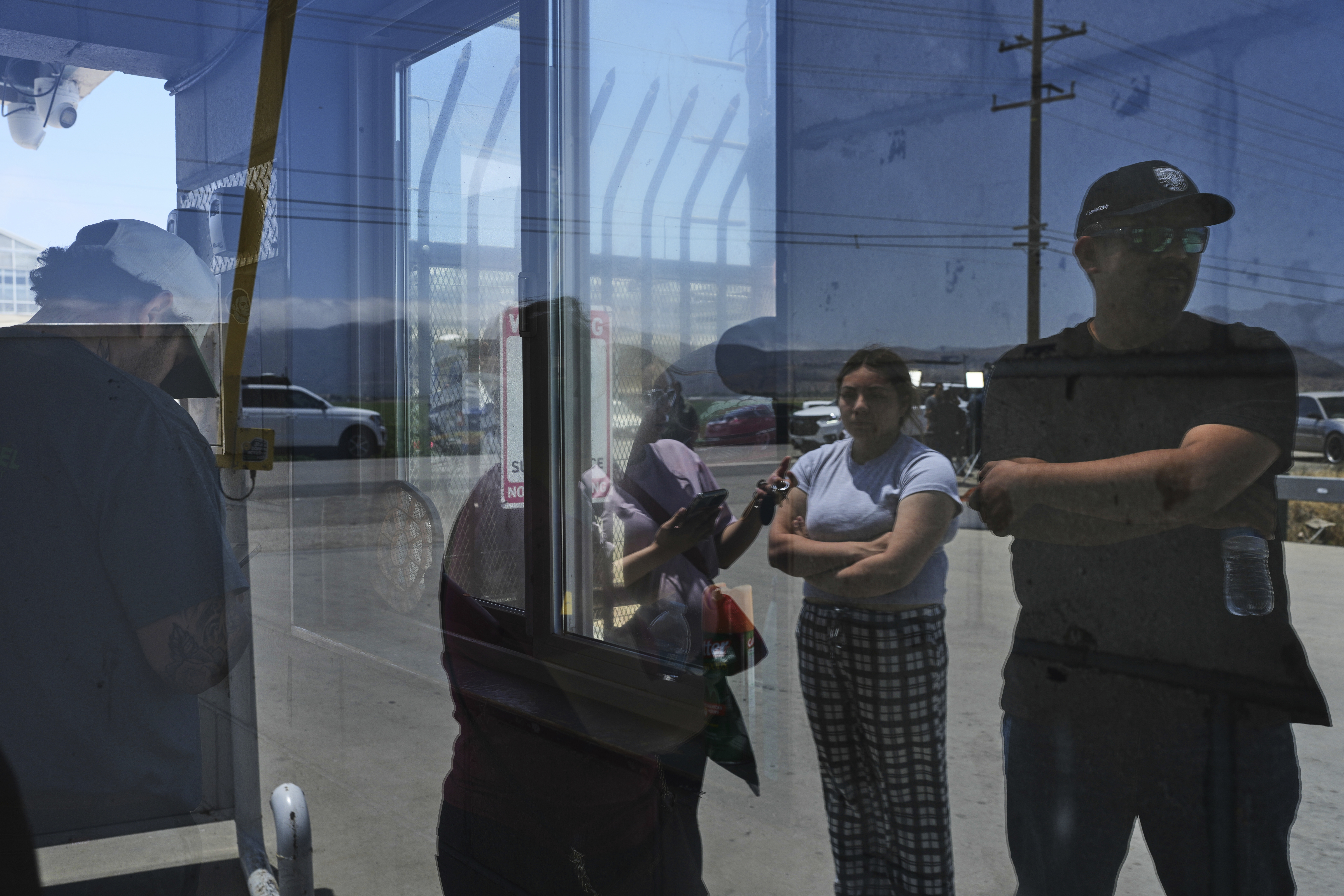 People wait outside of Glass House Farms, a day after an immigration raid on the facility, Friday, July 11, 2025, in Camarillo, Calif. (AP Photo/Jae C. Hong)