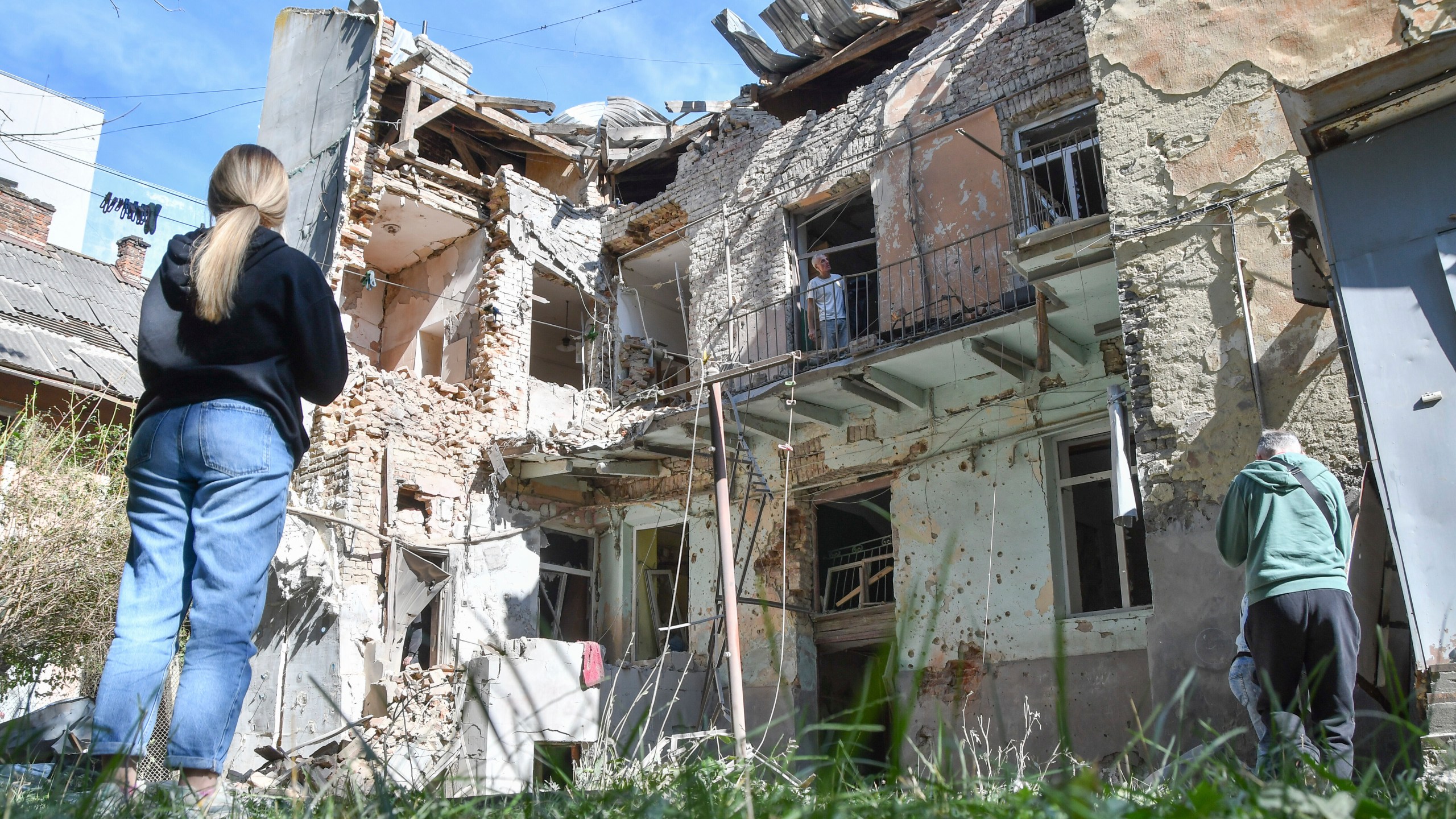 People look at a damaged residential building following Russian air attack in Lviv, Ukraine, Saturday, July 12, 2025. (AP Photo/Mykola Tys)