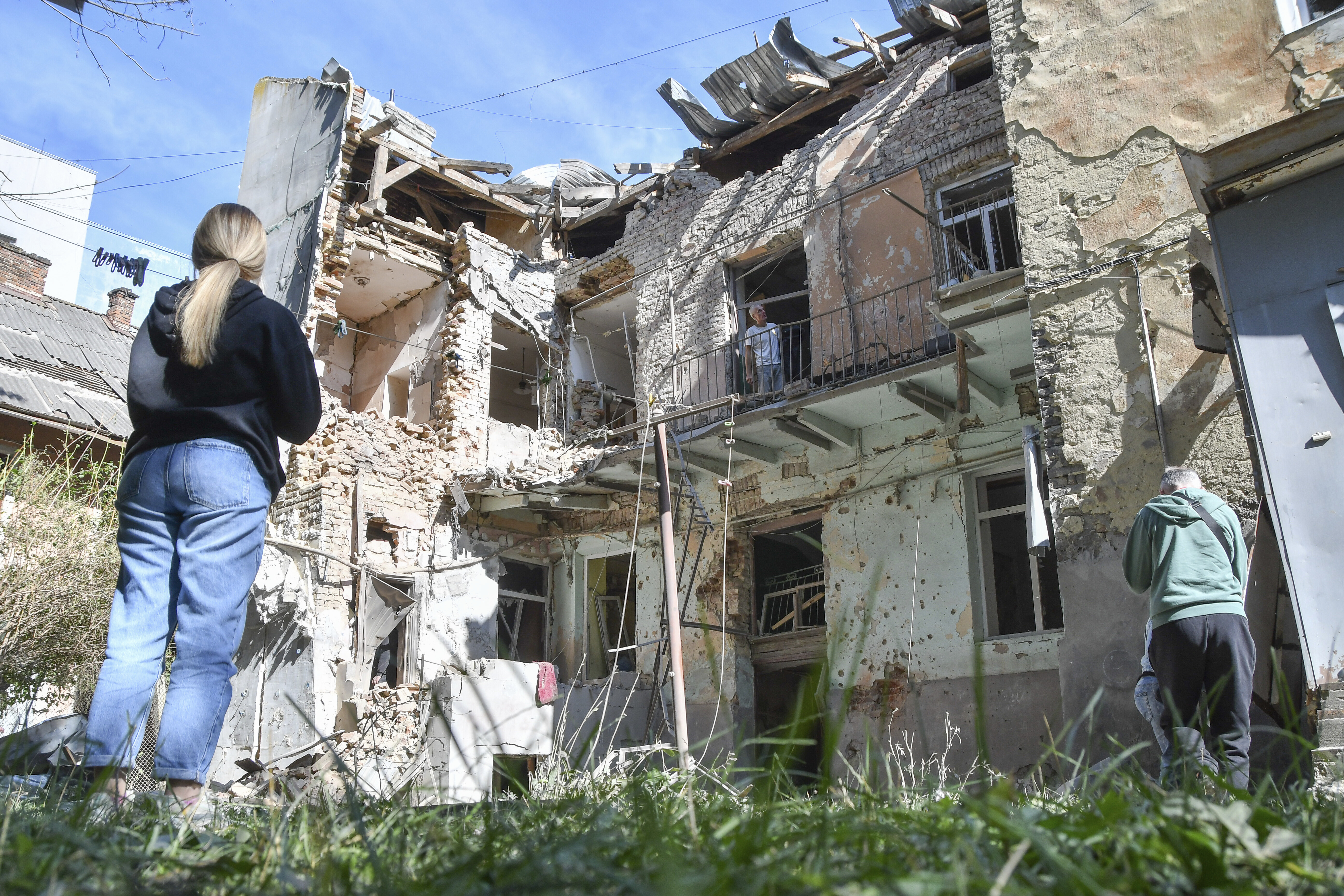 People look at a damaged residential building following Russian air attack in Lviv, Ukraine, Saturday, July 12, 2025. (AP Photo/Mykola Tys)