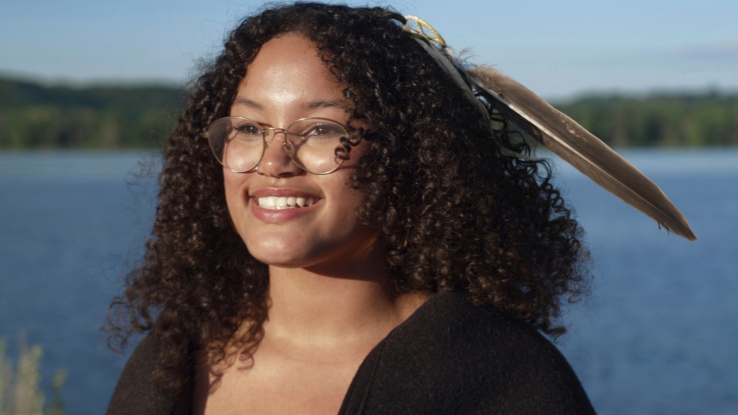 Jayvionna Buck poses for a portrait by the Mississippi River with the new bald eagle feather she received at a ceremony honoring high school graduates like her at the Prairie Island Indian Community in Minnesota on Wednesday, July 9, 2025. (AP Photo/Mark Vancleave)