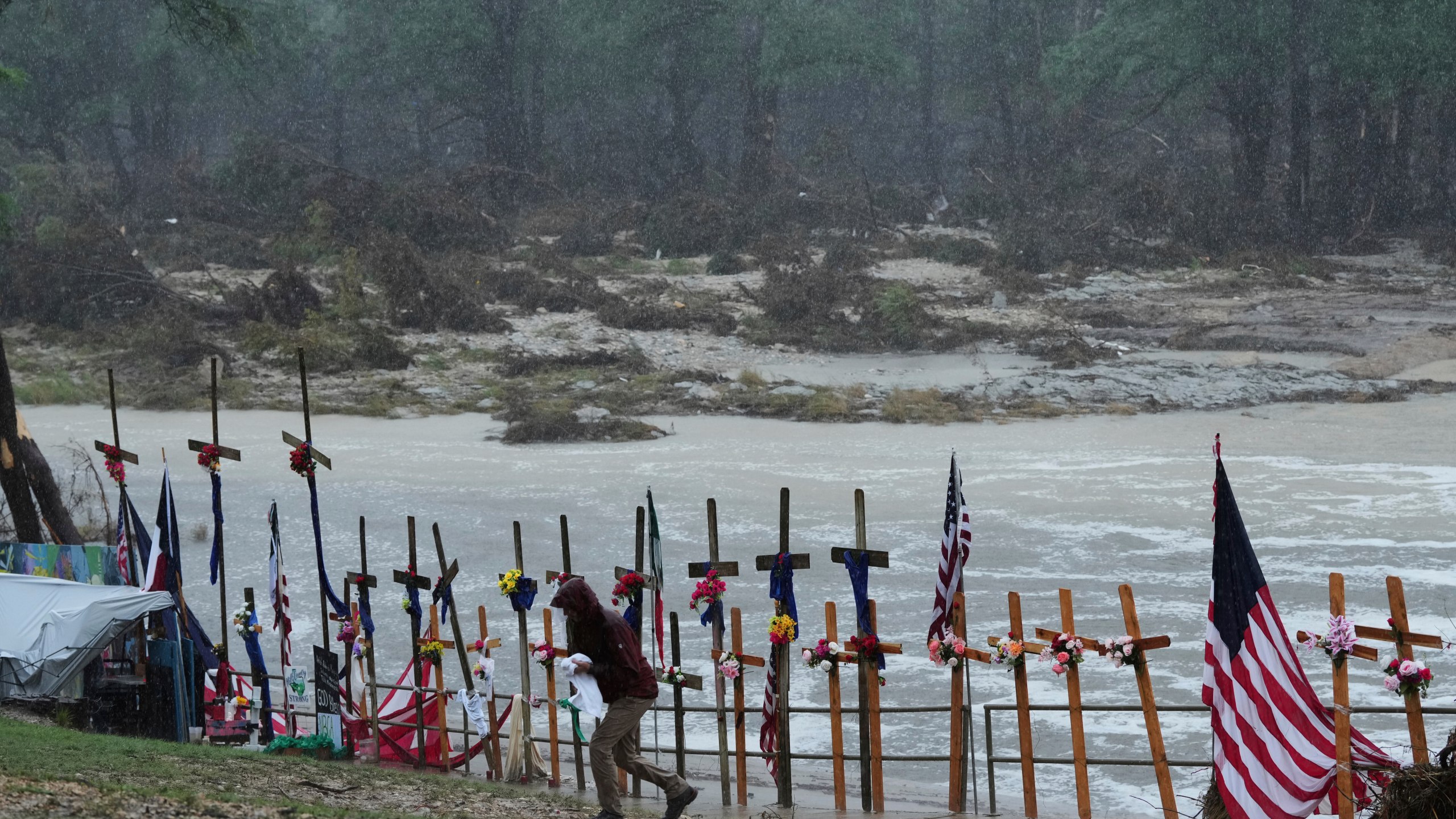 Rain falls over a makeshift memorial for flood victims along the Guadalupe River, Sunday, July 13, 2025, in Kerrville, Texas. (AP Photo/Eric Gay)
