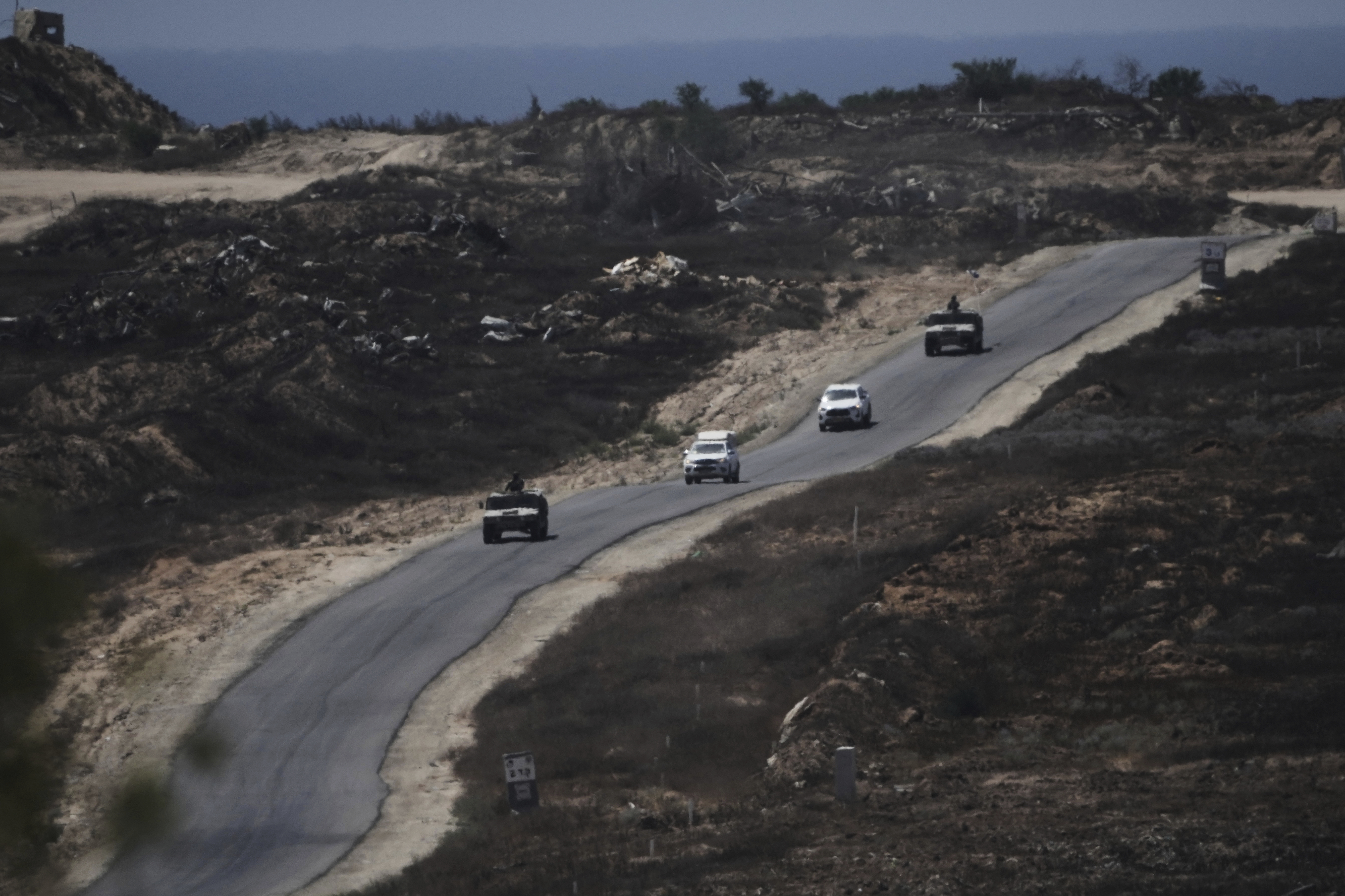 A convoy of Israel- military vehicles leaves the Gaza Strip near the Israel-Gaza border, seen from southern Israel, Monday, July 14, 2025. (AP Photo/Maya Alleruzzo)
