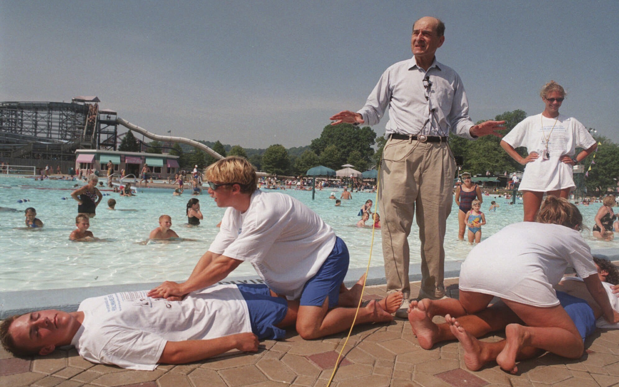 FILE - Dr. Henry J. Heimlich uses lifegaurds at Coney Island swimming pool in suburban Cincinnati on Friday, July 9, 1999, to demonstrate how the Heimlich maneuver can help save people from drowning. (AP Photo/Tony Tribble, File)