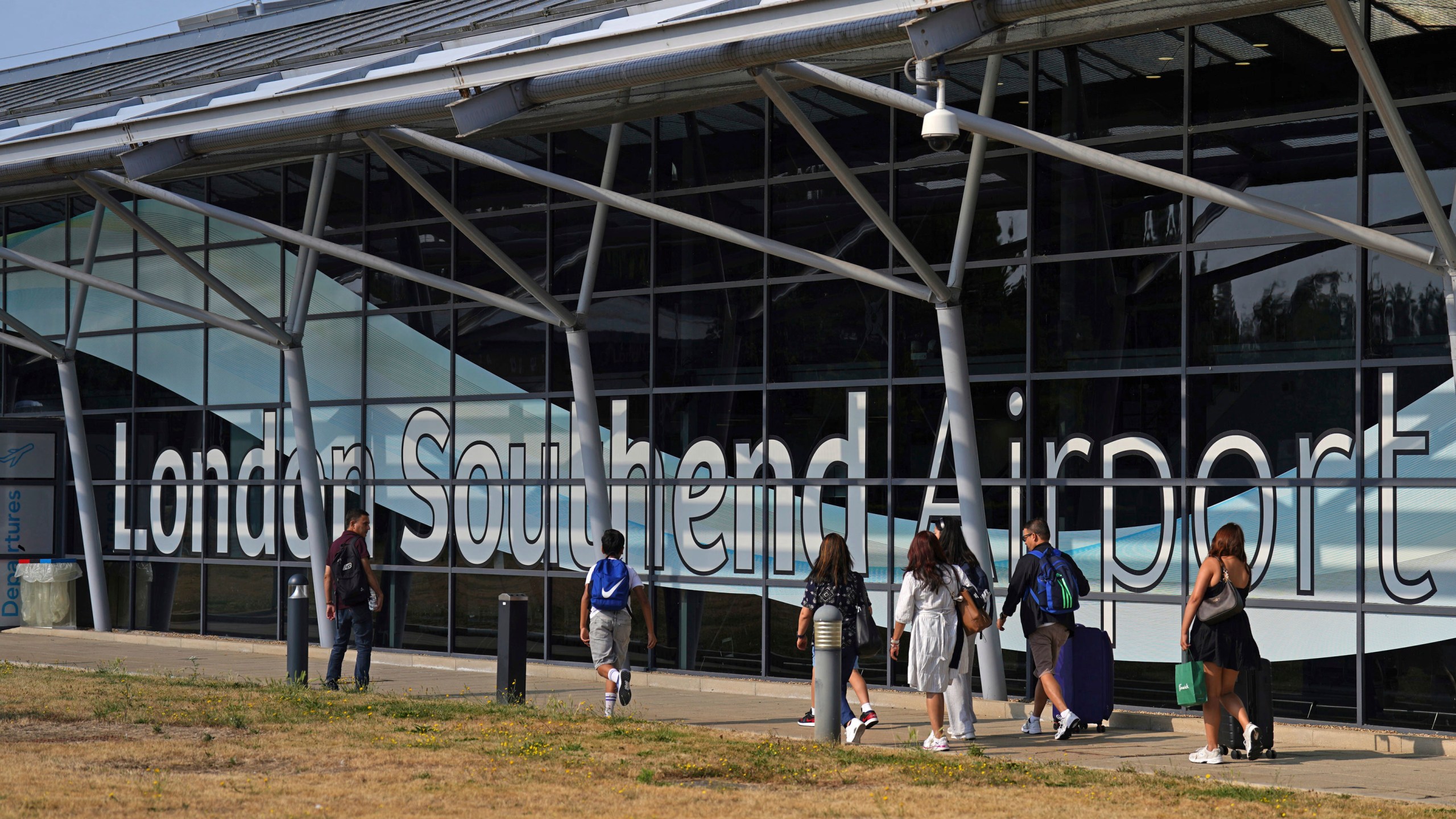 Passengers outside the terminal building at Southend Airport in Essex, where a 12-metre plane crashed shortly after take off on Sunday afternoon, Monday July 14, 2025. (Joe Giddens/PA via AP)