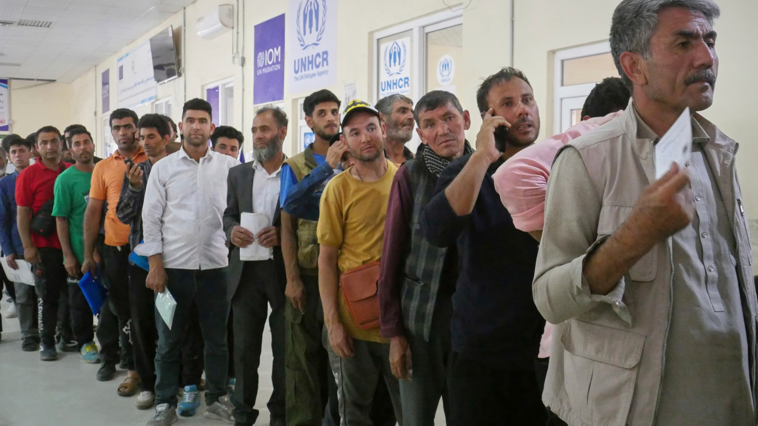 Afghan refugees who returned after fleeing Iran to escape deportation and conflict line up at a UNHCR facility near the Islam Qala crossing in western Herat province, Afghanistan, on Friday, June 20, 2025. (AP Photo/Omid Haqjoo)
