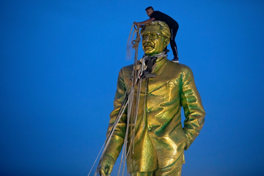 FILE - A man climbs to tie a rope around the head of a large statue of Sheikh Mujibur Rahman, father of Bangladesh leader Sheikh Hasina, as protesters try to bring it down after she resigned as Prime Minister, in Dhaka, Bangladesh, on Aug. 5, 2024. (AP Photo/Rajib Dhar, File)