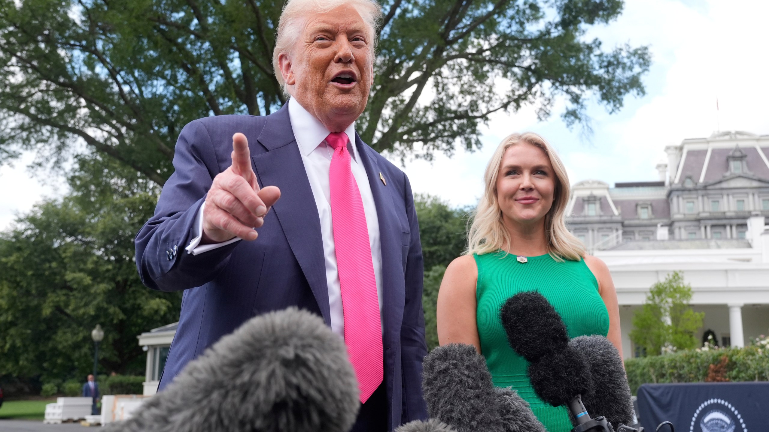 President Donald Trump speaks to the media as he leaves the White House, Tuesday, July 15, 2025, in Washington, as White House press secretary Karoline Leavitt, looks on. (AP Photo/Manuel Balce Ceneta)