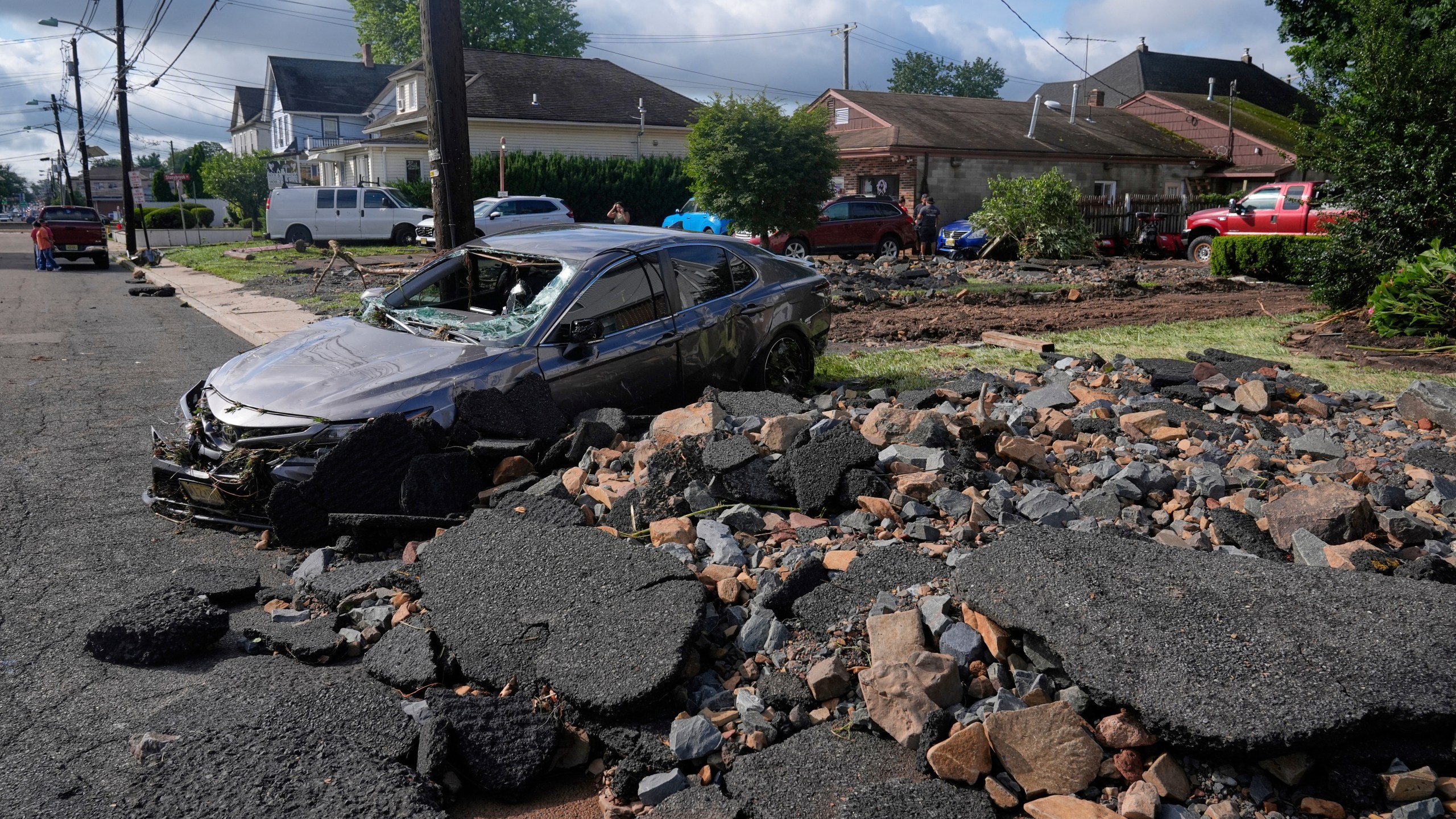 Debris, rubble and a damaged car lie on a street after flooding from rains in the area of North Plainfield, N.J., Tuesday, July 15, 2025. (AP Photo/Seth Wenig)
