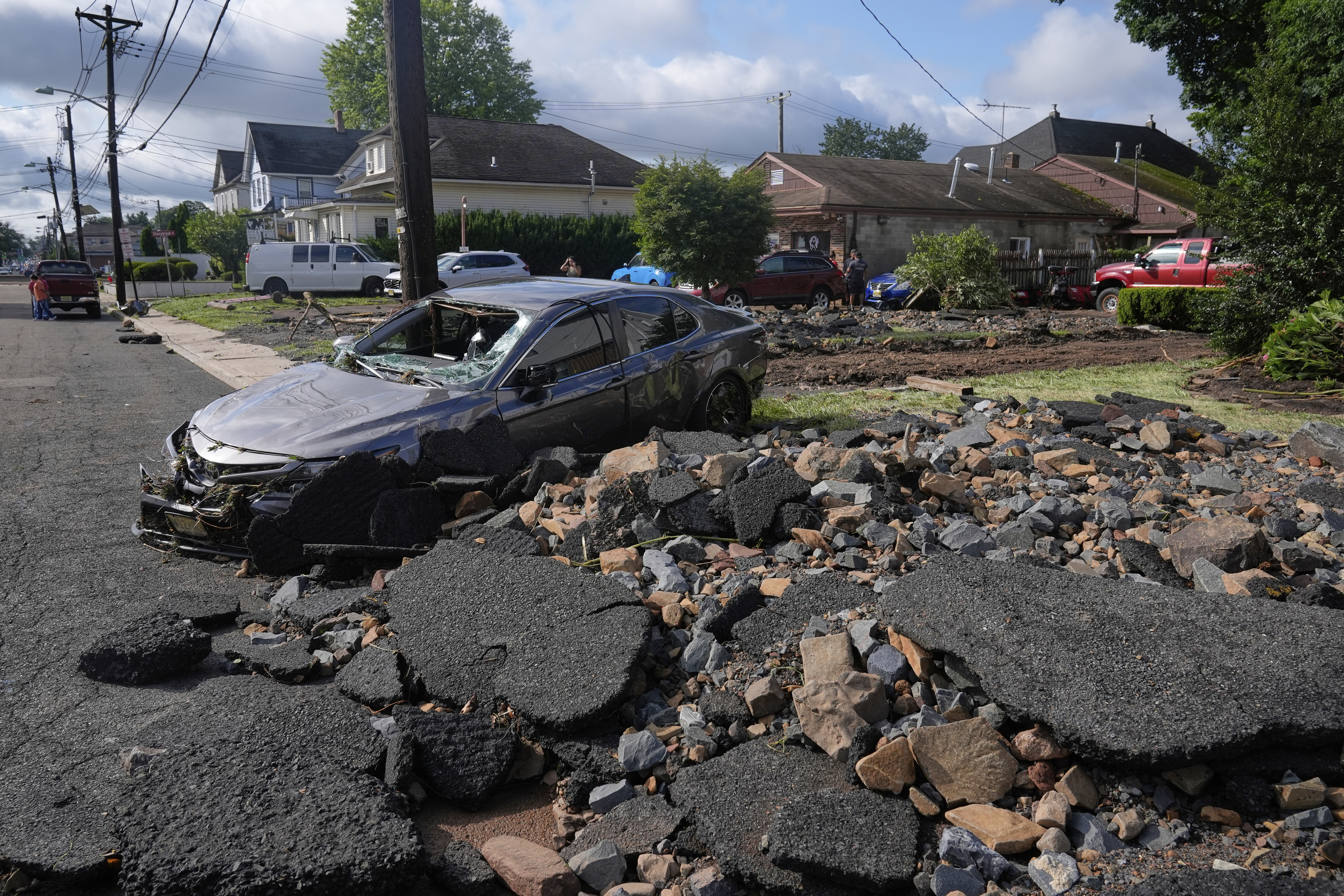Debris, rubble and a damaged car lie on a street after flooding from rains in the area of North Plainfield, N.J., Tuesday, July 15, 2025. (AP Photo/Seth Wenig)