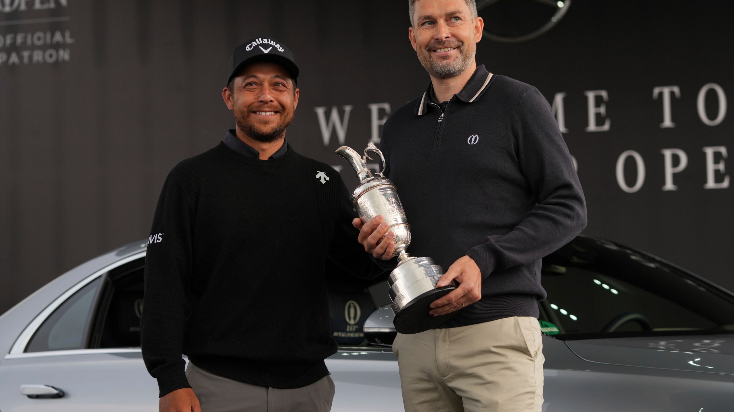Xander Schauffele of the United States, left, winner of the 2024 British Open, hands back the Claret Jug trophy to the R&A CEO Mark Darbon ahead of the 2025 British Open golf championship at the Royal Portrush Golf Club, Northern Ireland, Monday, July 14, 2025. (AP Photo/Fransisco Seco)