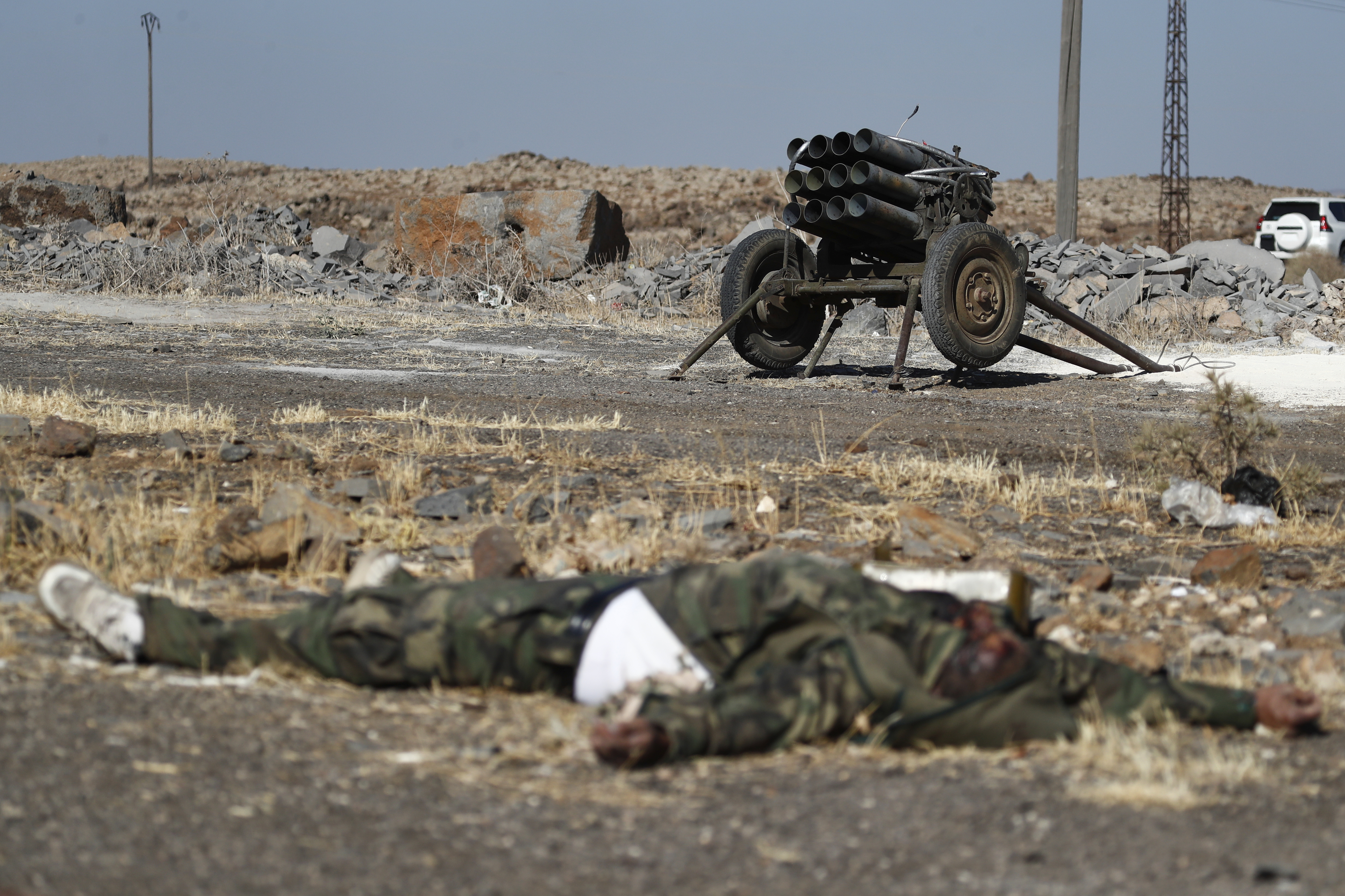 A dead fighter of the Druze militias lies on the ground in front of a rocket launcher on the outskirts of Sweida city, where clashes erupted between Sunni Bedouin clans and Druze militias, southern Syria, Monday, July 14, 2025. (AP Photo/Omar Sanadiki)