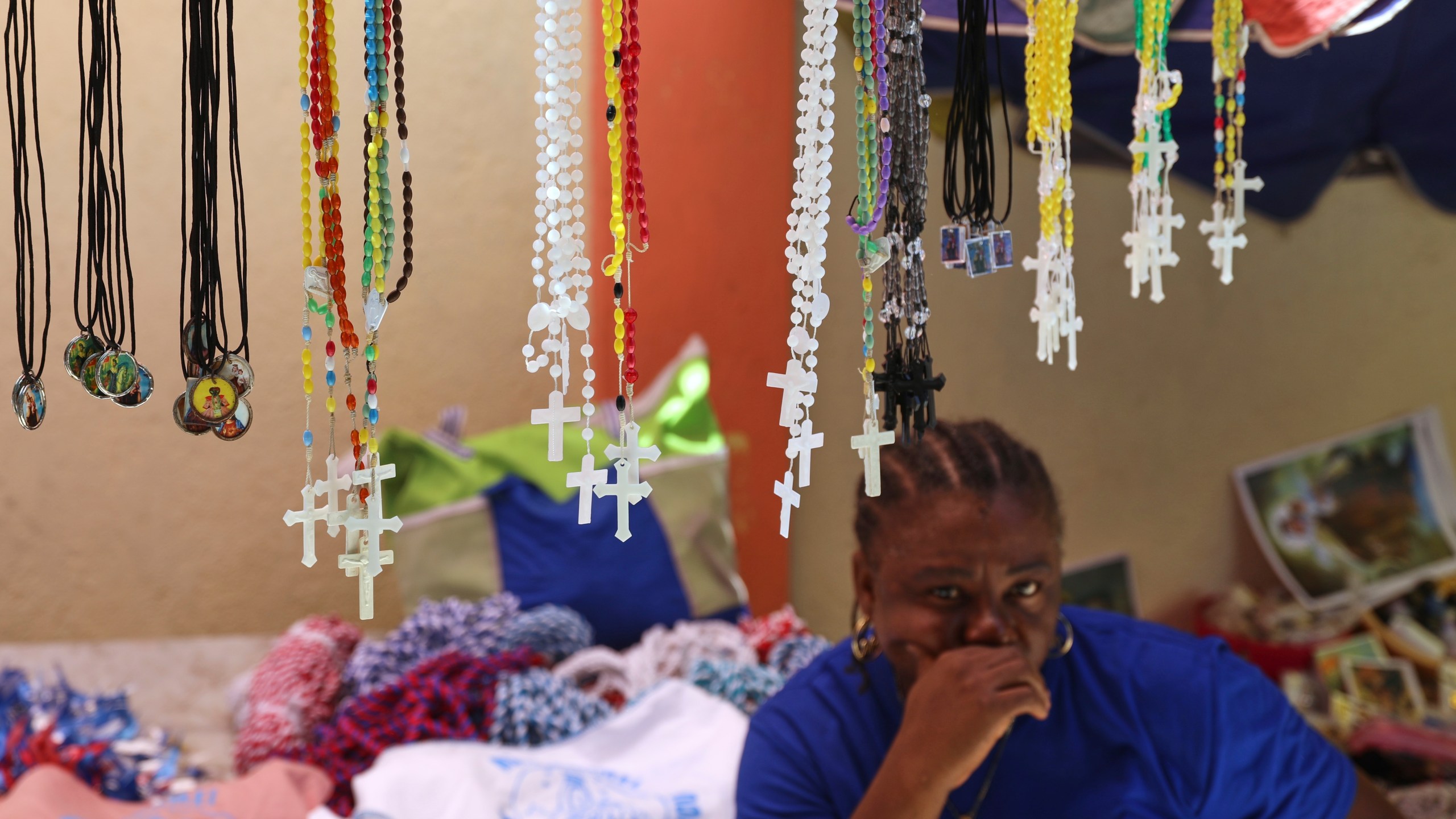Rosaries for sale hang from a vendor's stand at the entrance of the Mount Carmel Church during a Mass marking the feast day of Our Lady of Mount Carmel, in the Petion-ville neighborhood of Port-au-Prince, Haiti, Wednesday, July 16, 2025.(AP Photo/Odelyn Joseph)