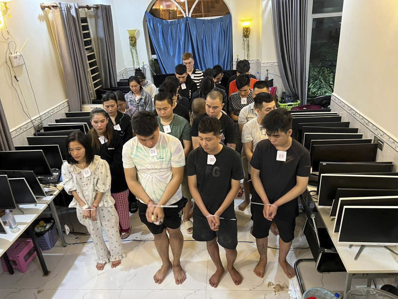 In this photo released by Agence Kampuchea Press (AKP), online scammers arrested by authorities stand in a building in Sihanoukville province, southwestern of Phnom Penh, Cambodia, Tuesday, July 15, 2025. (AKP via AP)