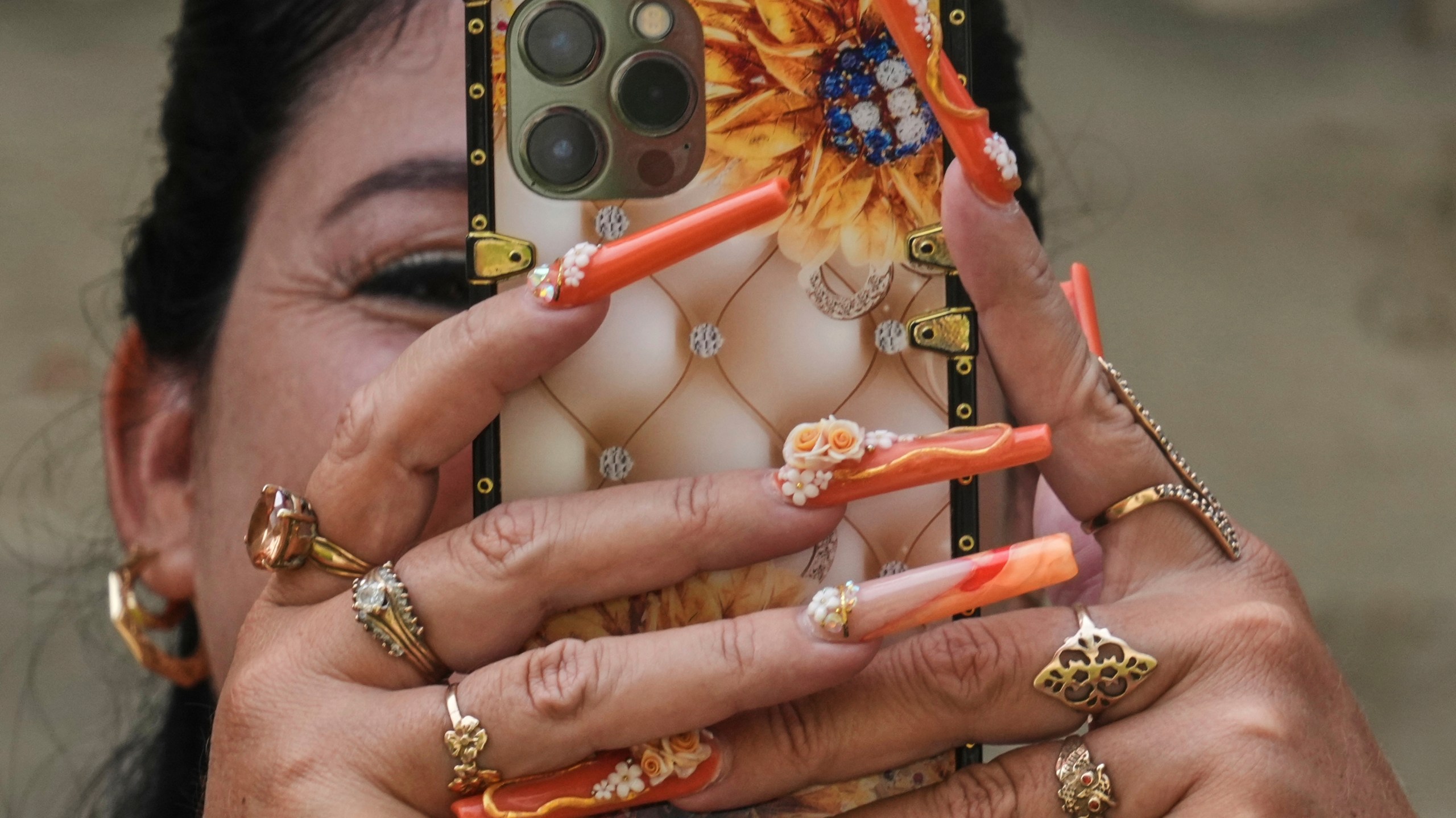 Miralys Maura Cruz sports long, decorative nails as she chats on her phone at home in La Gallega, Havana province, Cuba, Saturday, June 28, 2025. (AP Photo/Ramon Espinosa)