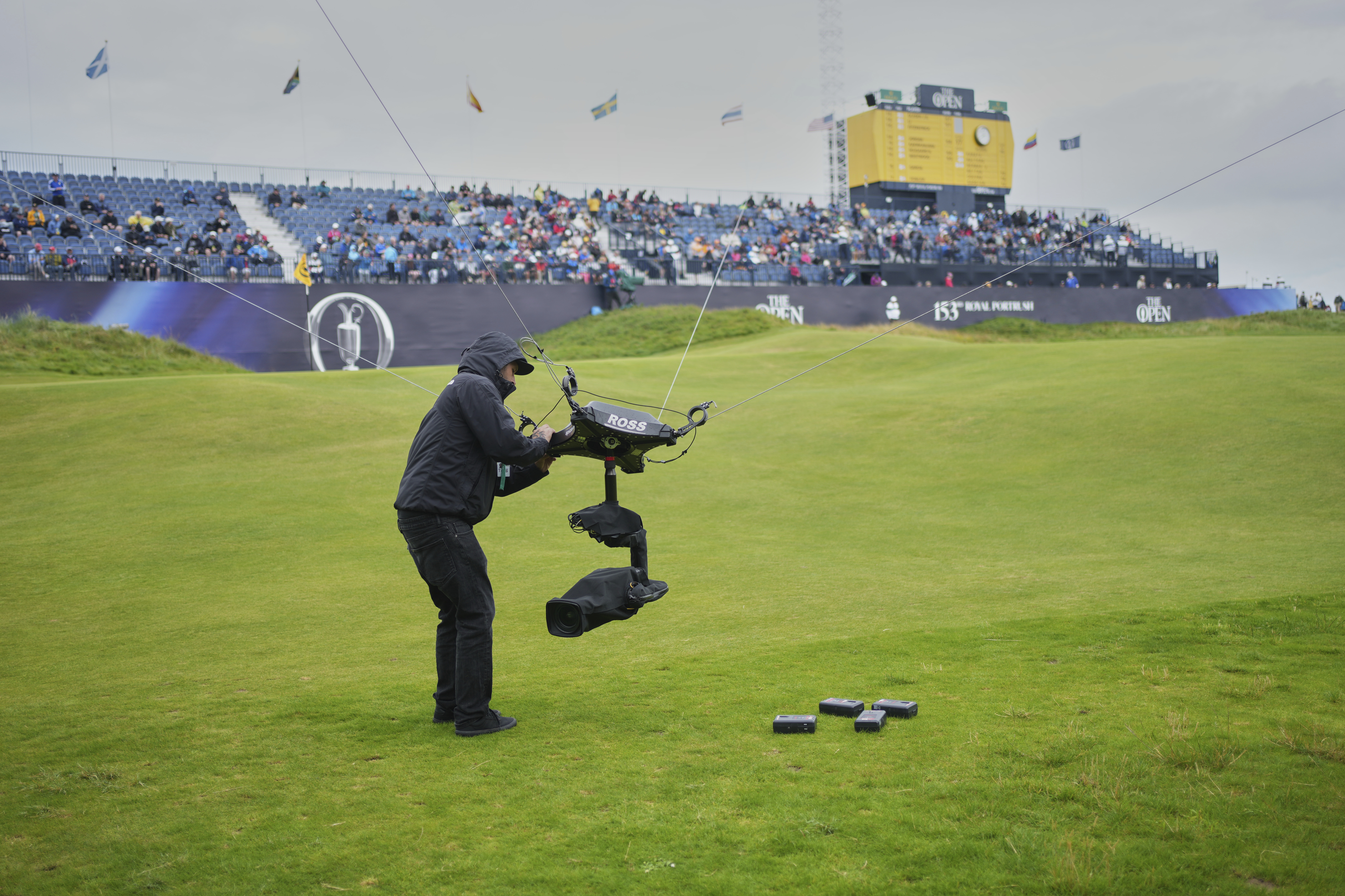 A technician changes the camera batteries on spidercam on the 18th green during the first round of the British Open golf championship at the Royal Portrush Golf Club, Northern Ireland, Thursday, July 17, 2025. (AP Photo/Jon Super)