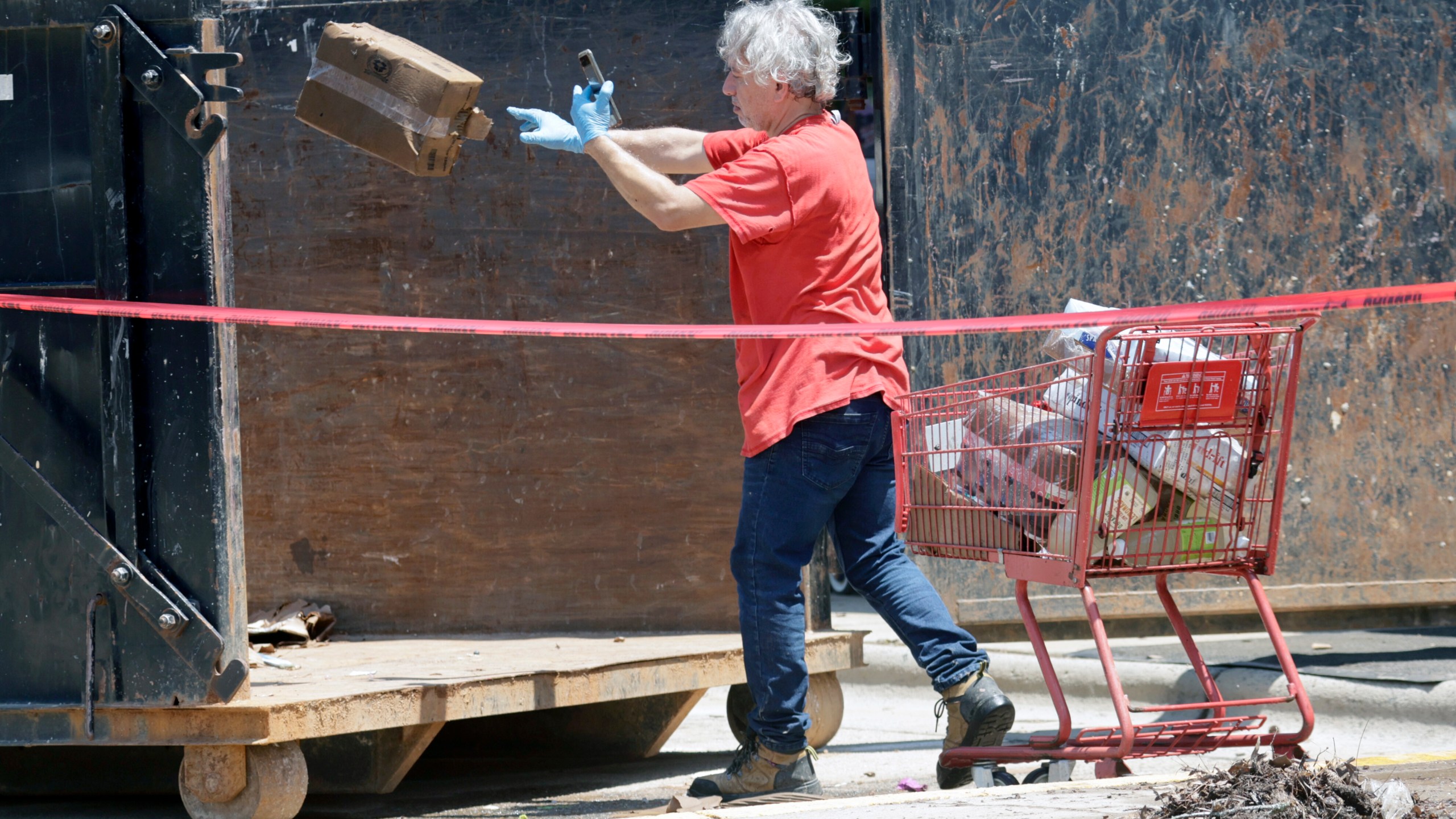A worker tosses damaged merchandise into a large dumpster at the Trader Joe's supermarket in the Eastgate shopping center after it was flooded out during tropical storm Chantal, Monday, July 7, 2025, in Chapel Hill, N.C. (AP Photo/Chris Seward)