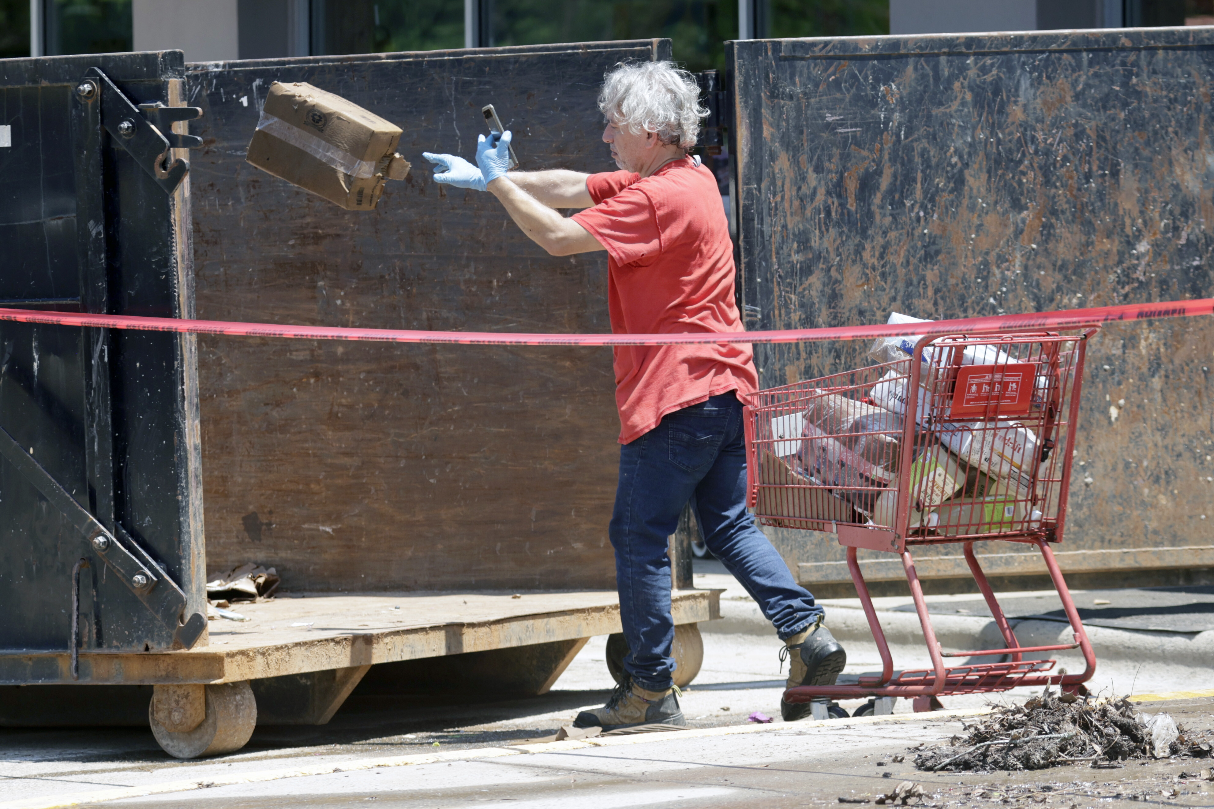 A worker tosses damaged merchandise into a large dumpster at the Trader Joe's supermarket in the Eastgate shopping center after it was flooded out during tropical storm Chantal, Monday, July 7, 2025, in Chapel Hill, N.C. (AP Photo/Chris Seward)