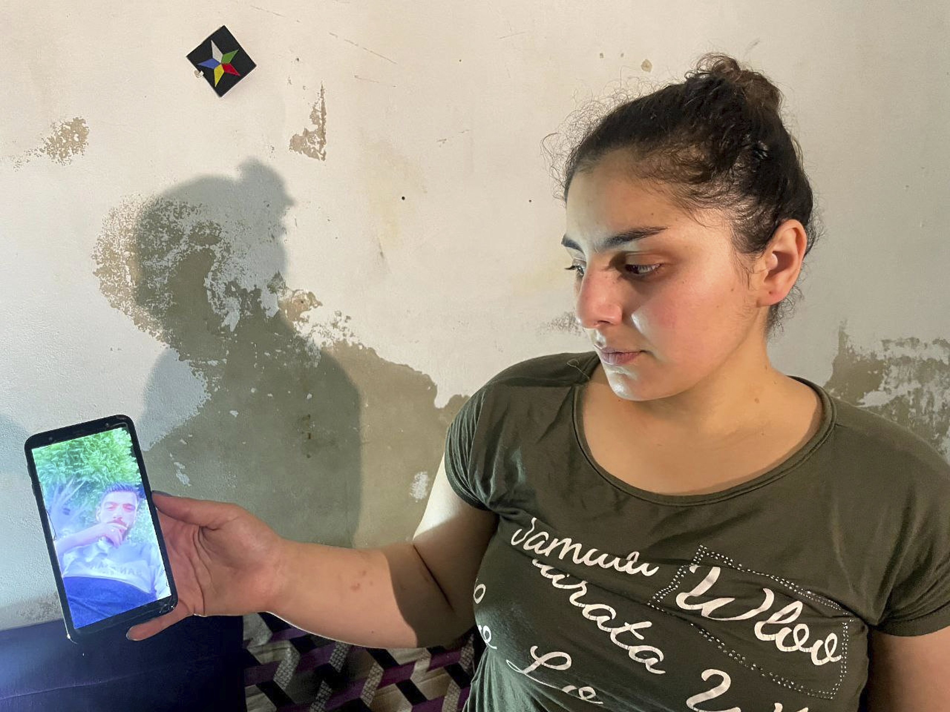 Druze woman, Evelyn Azzam, 20, shows a picture of her husband who was wounded in clashes between Syrian government forces and Druze militias in Sweida, during an interview with The Associated Press in the southern Damascus suburb of Jaramana, Wednesday, July 16, 2025. (AP Photo/Abdulrahman Shaheen)