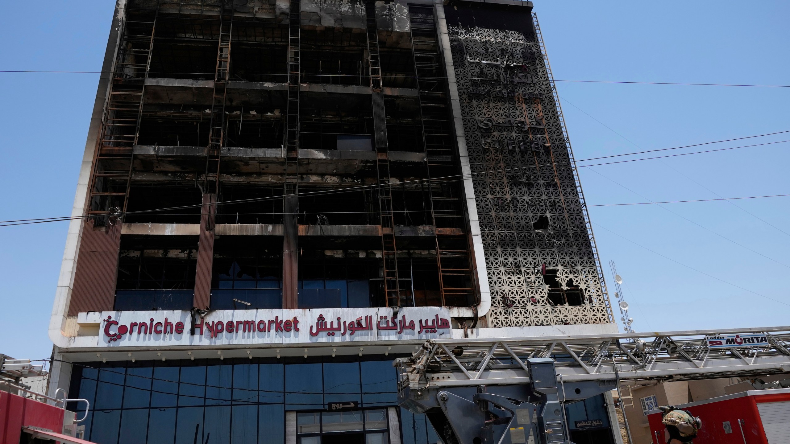 Iraqi security forces gather in front of a burning hypermarket building in Kut, Iraq, Thursday, July 17, 2025. (AP Photo/Hadi Mizban)