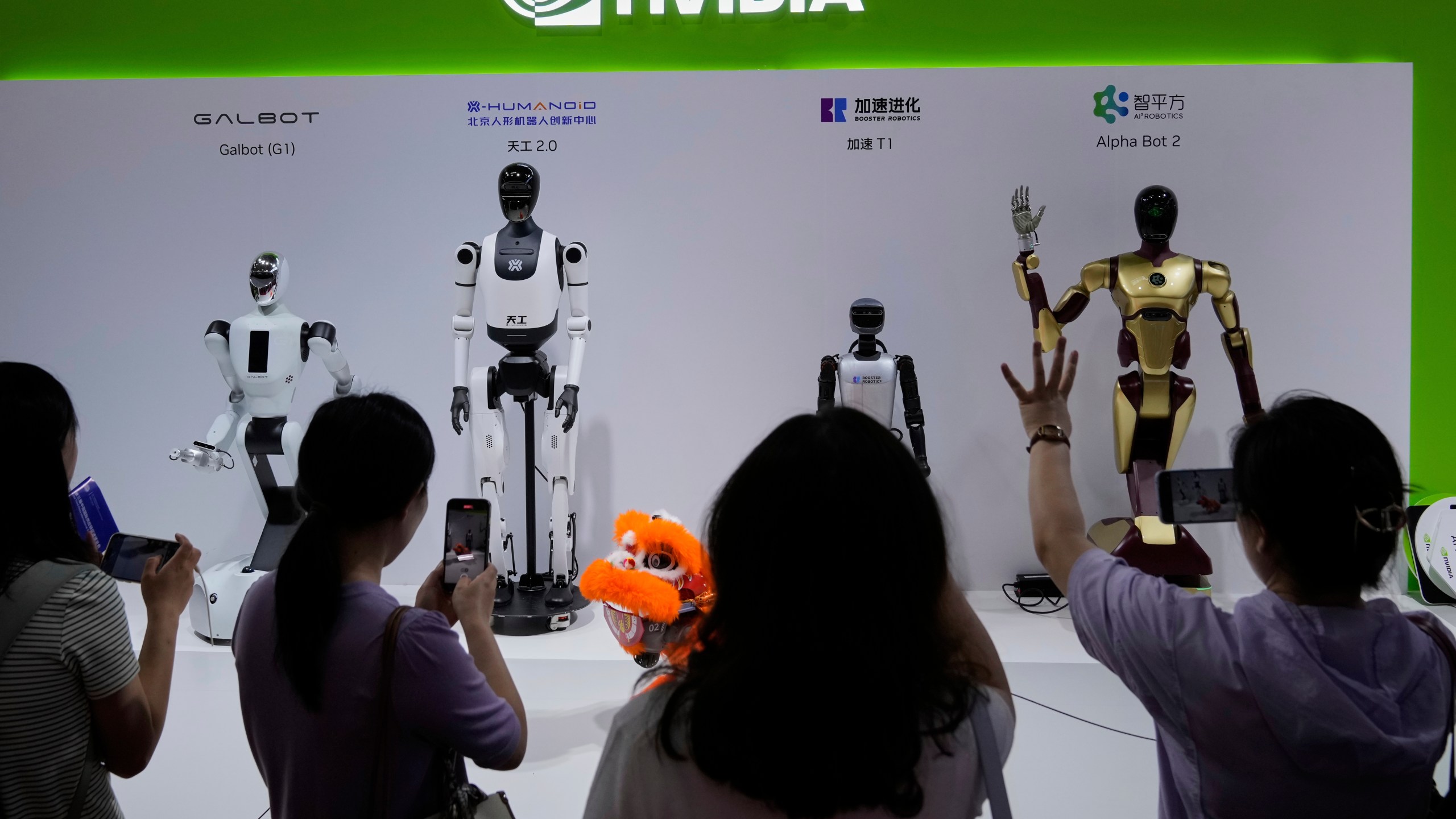 Visitors give commands to a robot at Nvidia's booth during the 3rd China International Supply Chain Expo at the China International Exhibition Center, in Beijing, China, Friday, July 18, 2025. (AP Photo/Mahesh Kumar A.)