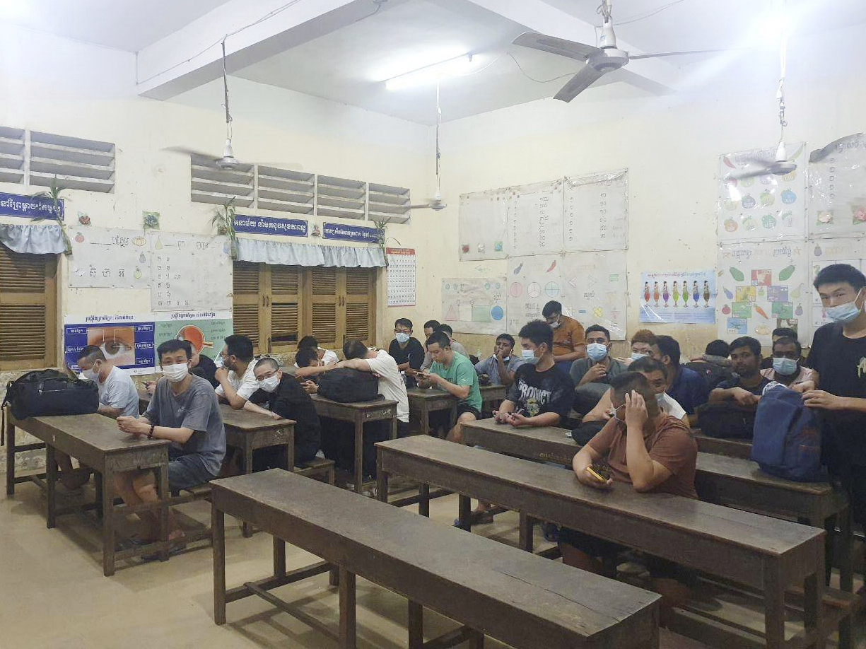 In this photo provided by state news service Agence Kampuchea Press, alleged online scammers arrested by authorities sit in a classroom on the outskirts of Phnom Penh, Cambodia, Friday, July 18, 2025. (AKP via AP)