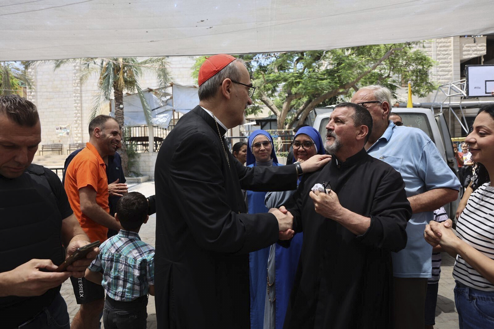 Latin Patriarch Cardinal Pierbattista Pizzaballa, center, speaks with a worshipper as part of a religious delegation to the Gaza Strip led by two patriarchs from Jerusalem visiting the Holy Family Catholic Church struck by an Israeli shell the day before in Deir al-Balah, Friday, July 18, 2025. (Latin Patriarchate of Jerusalem via AP)