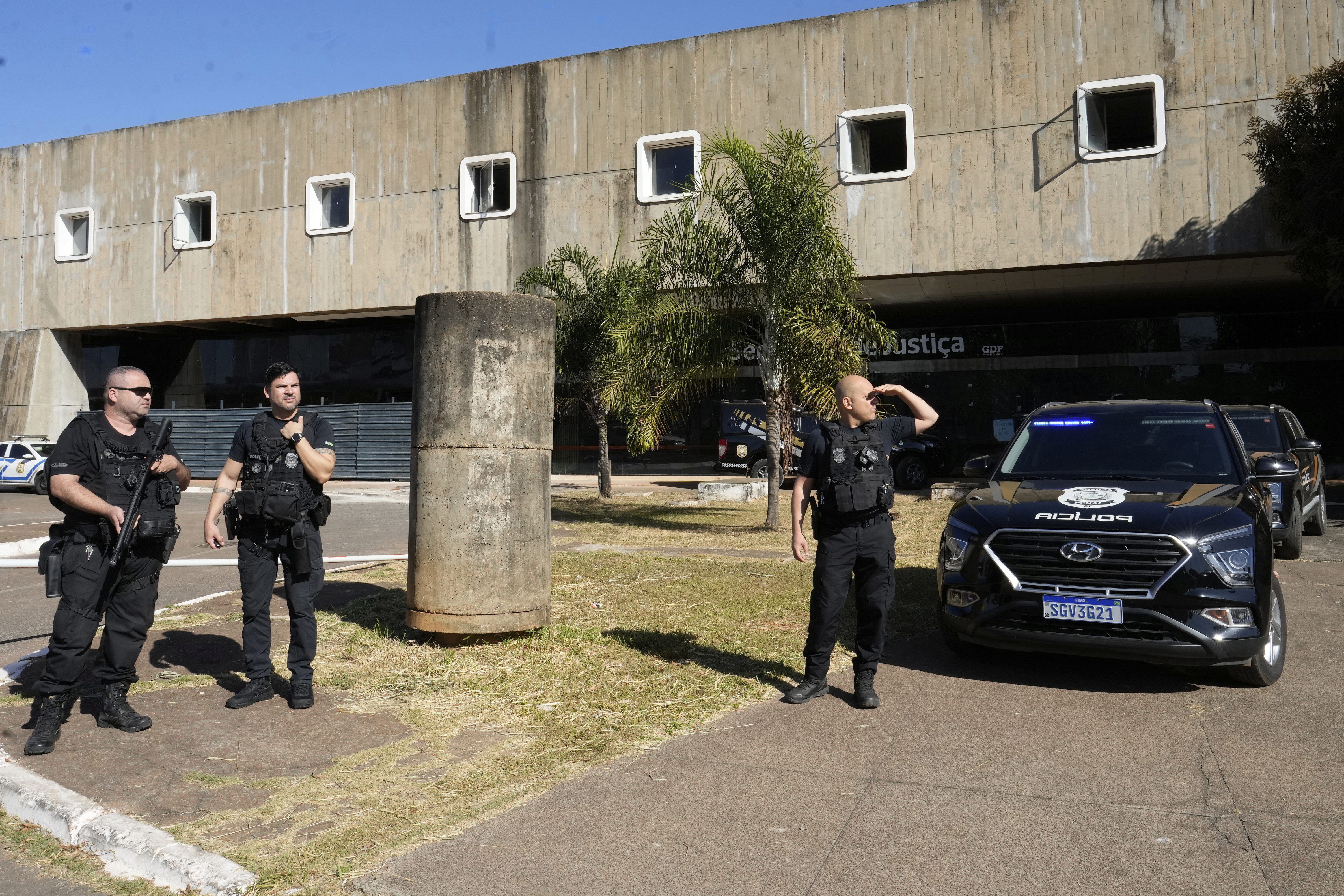 Federal police stand outside the Secretariat of Penitentiary Administration office where Brazil's former President Jair Bolsonaro arrived after the Supreme Court ordered him to be fitted with an electronic ankle monitor, in Brasilia, Brazil, Friday, July 18, 2025. (AP Photo/Eraldo Peres)