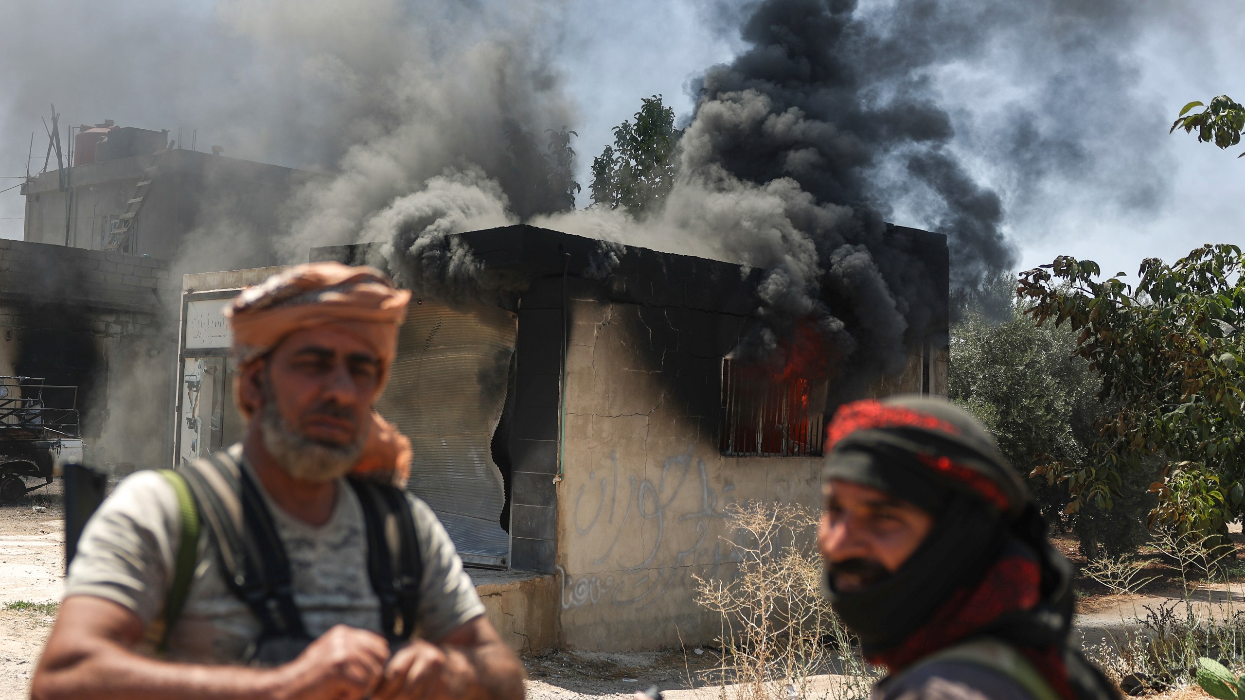 Bedouin fighters stand in front a burned shop at Mazraa village on the outskirts of Sweida city, during clashes between the Bedouin clans and Druze militias, southern Syria, Friday, July 18, 2025. (AP Photo/Ghaith Alsayed)