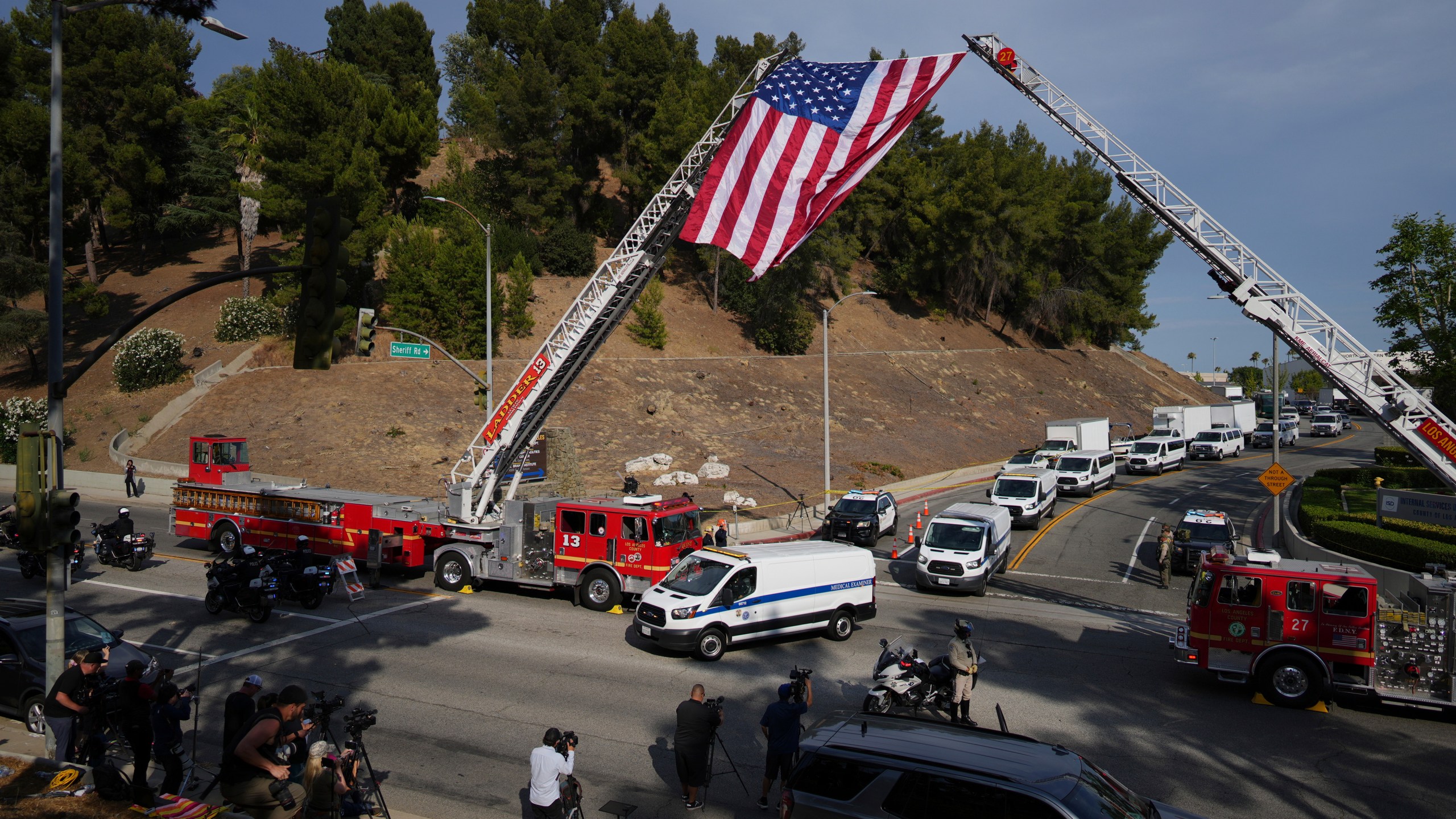 Medical examiner vans are driven along a procession route near where an explosion at a training facility killed three sheriff's deputies on Friday, July 18, 2025, in Los Angeles. (AP Photo/Eric Thayer)