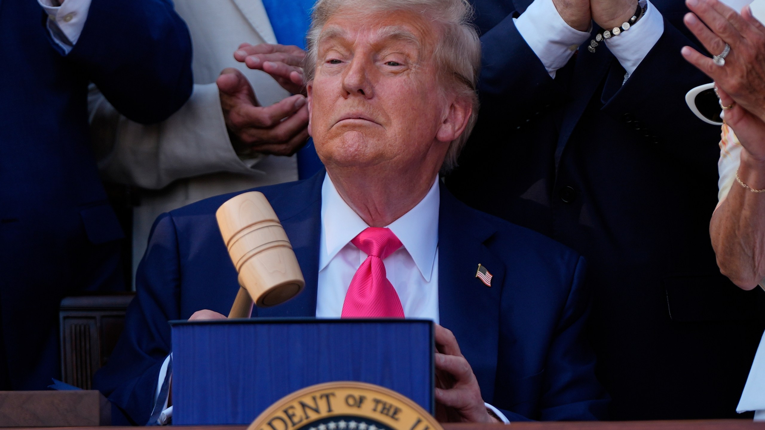 President Donald Trump holds a gavel after he signed his signature bill of tax breaks and spending cuts at the White House, Friday, July 4, 2025, in Washington, surrounded by members of Congress. (AP Photo/Julia Demaree Nikhinson)