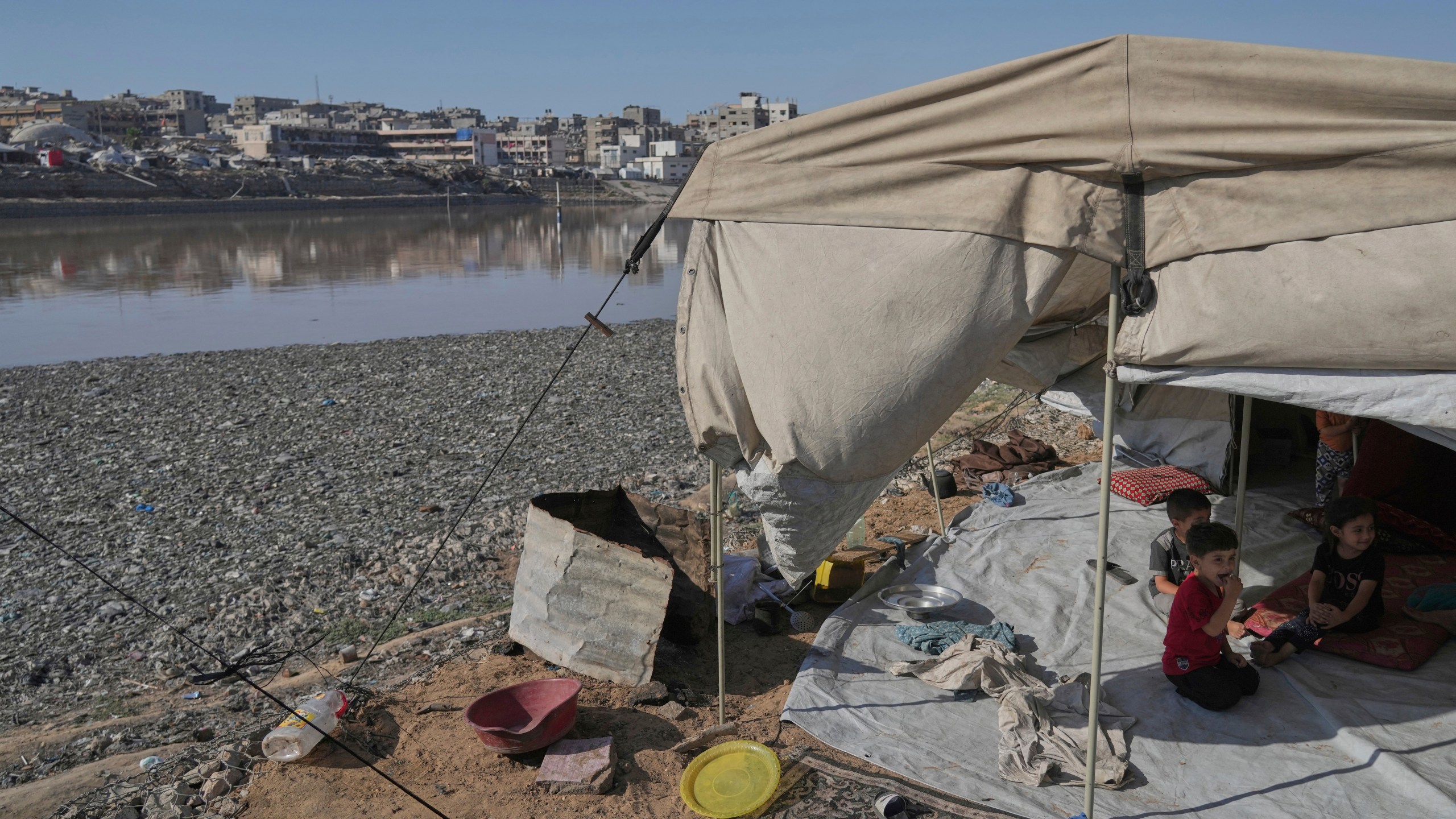 Children sit in their tent at a camp for displaced Palestinians, located near a rainwater collection reservoir that has been contaminated by sewage and garbage following the Israeli air and ground operations in Gaza City, Friday, July 18, 2025. (AP Photo/Jehad Alshrafi)