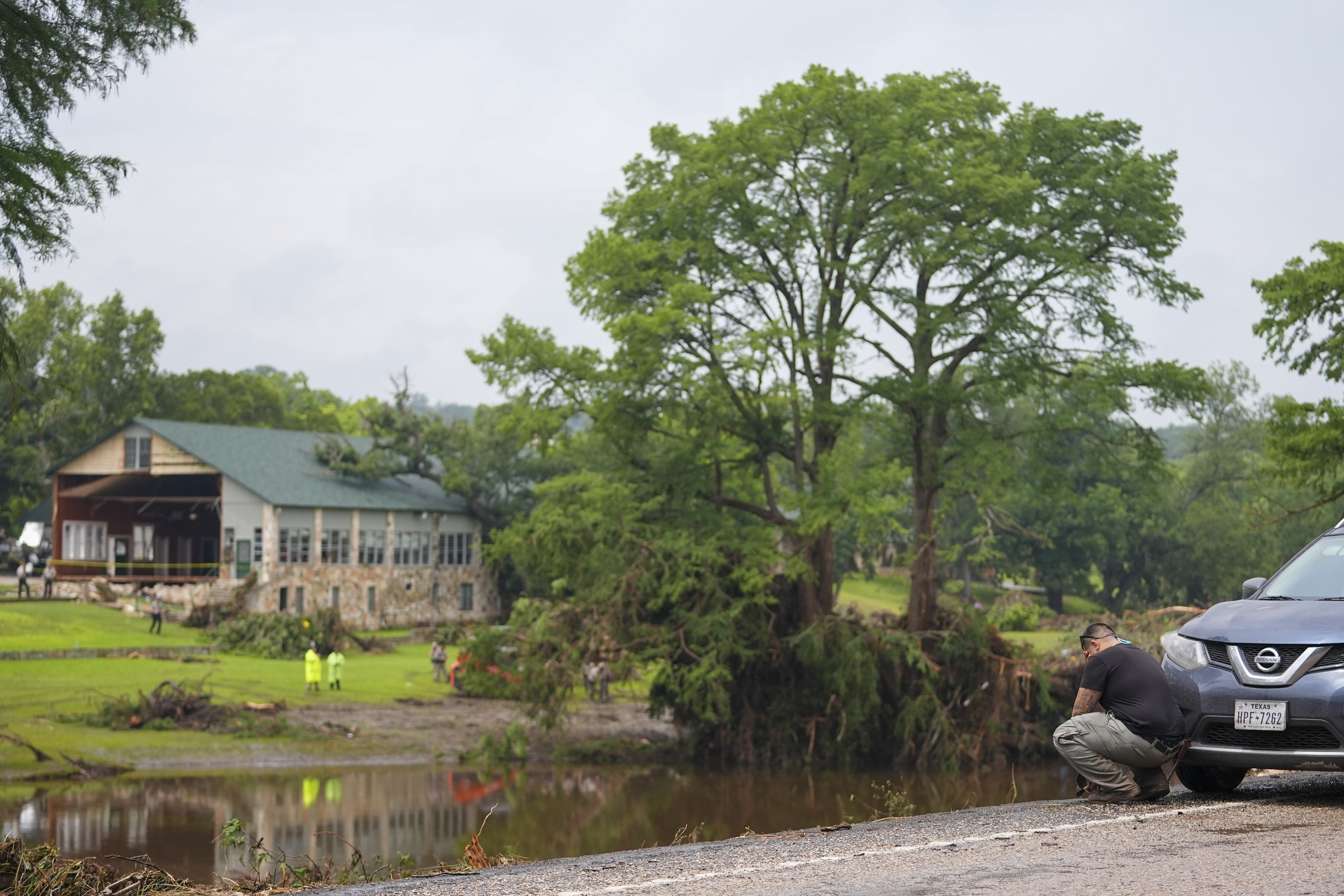 Avi Santos, 23, of San Antonio, Texas, reacts while stopping on the road alongside at Camp Mystic along the banks of the Guadalupe River after a flash flood swept through the area Sunday, July 6, 2025, in Hunt, Texas. (AP Photo/Julio Cortez)