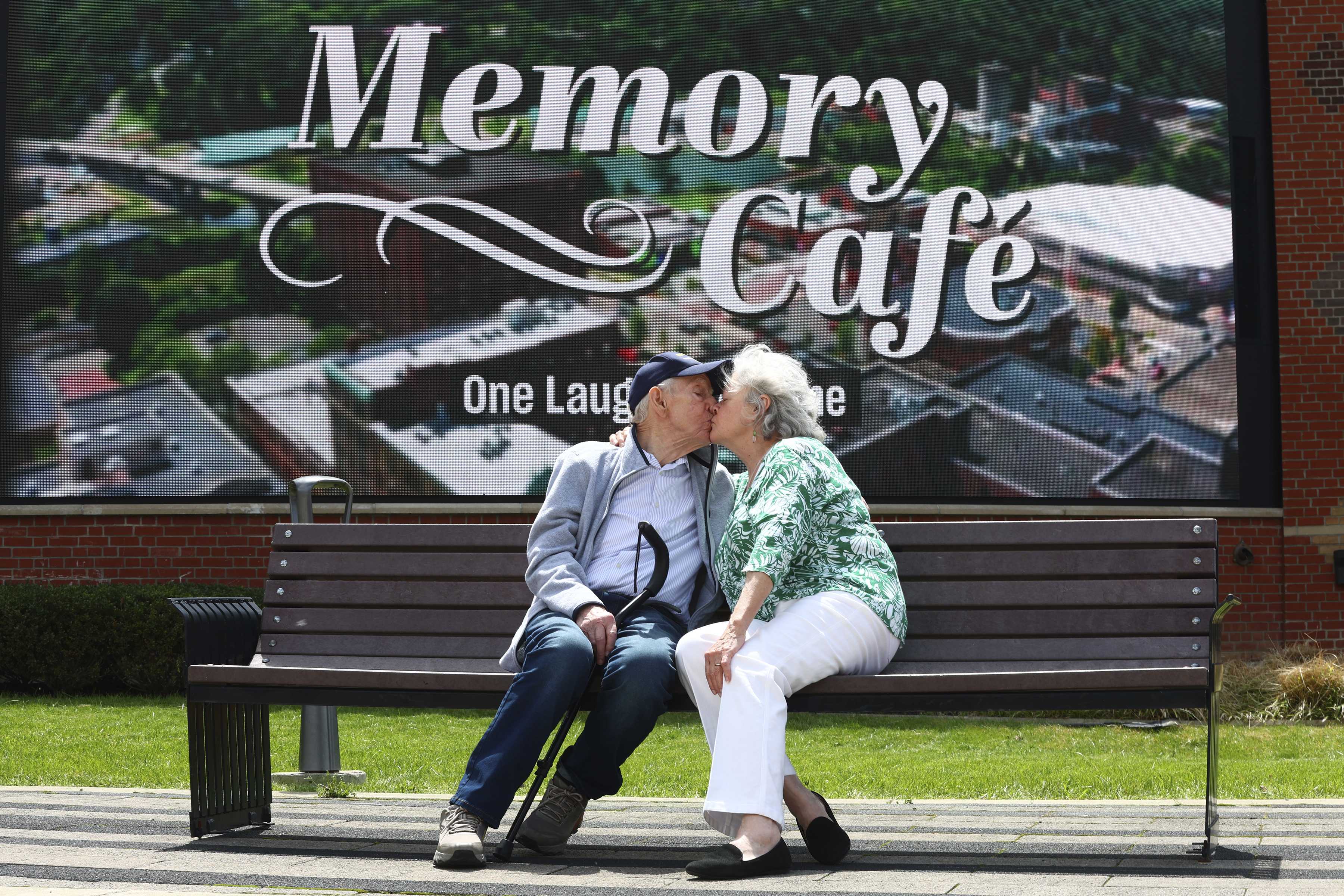 Mario and Gail Cirasunda, of Orchard Park, N.Y., share a kiss on a bench following a Memory Cafe event at the National Comedy Center Monday, May 5, 2025, in Jamestown, N.Y. (AP Photo/Jeffrey T. Barnes)
