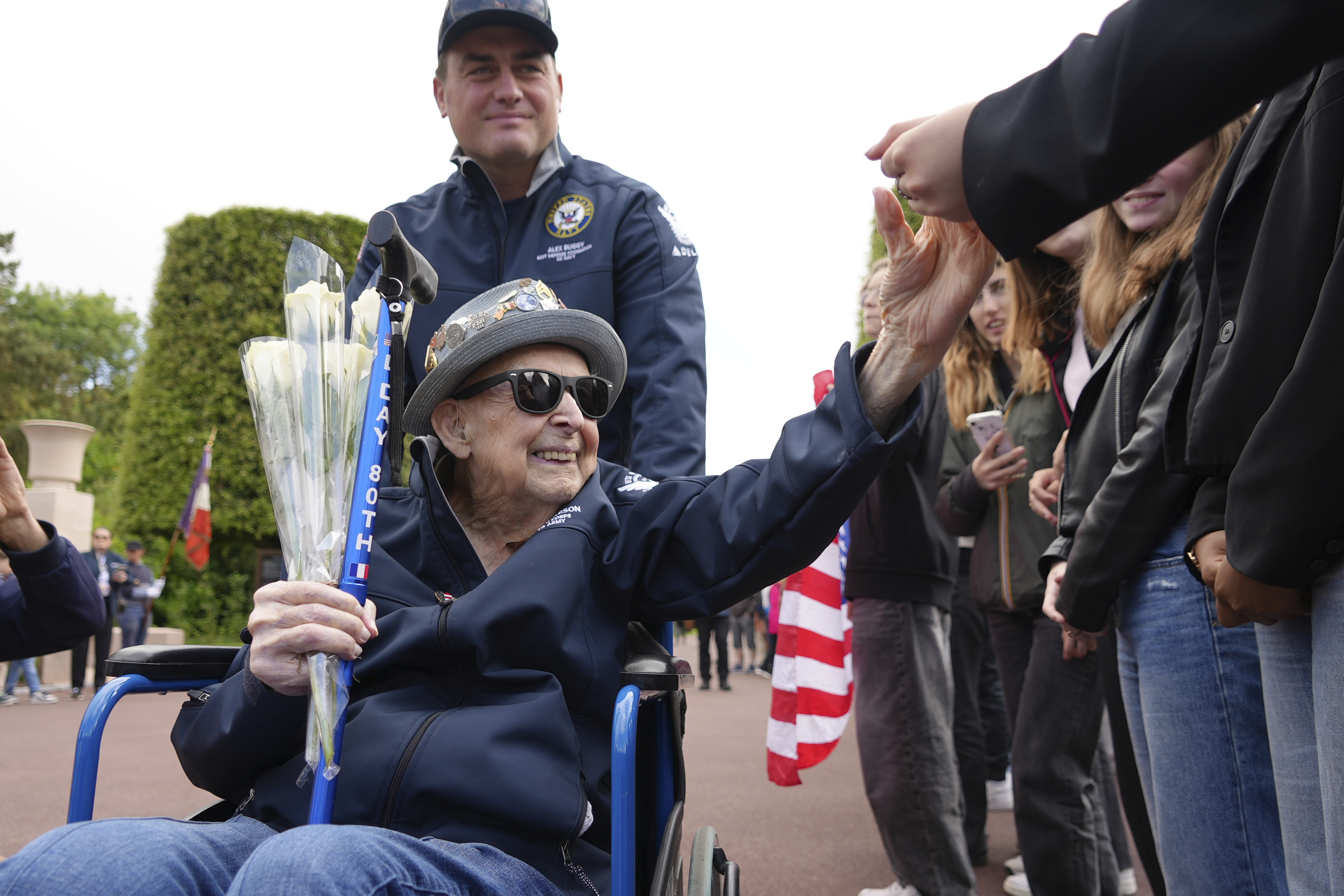 FILE - D-Day veteran Jake Larson, a 102-year-old who is also a star on TikTok, with 1.2 million followers, greets schoolchildren during a visit on June 2, 2025 in Colleville-sur-Mer, to the Normandy American Cemetery that is the final resting place for nearly 9,400 American war dead and which overlooks Omaha beach, one of the D-D-day invasion zones on June 6, 1944. (AP Photo/John Leicester, File)