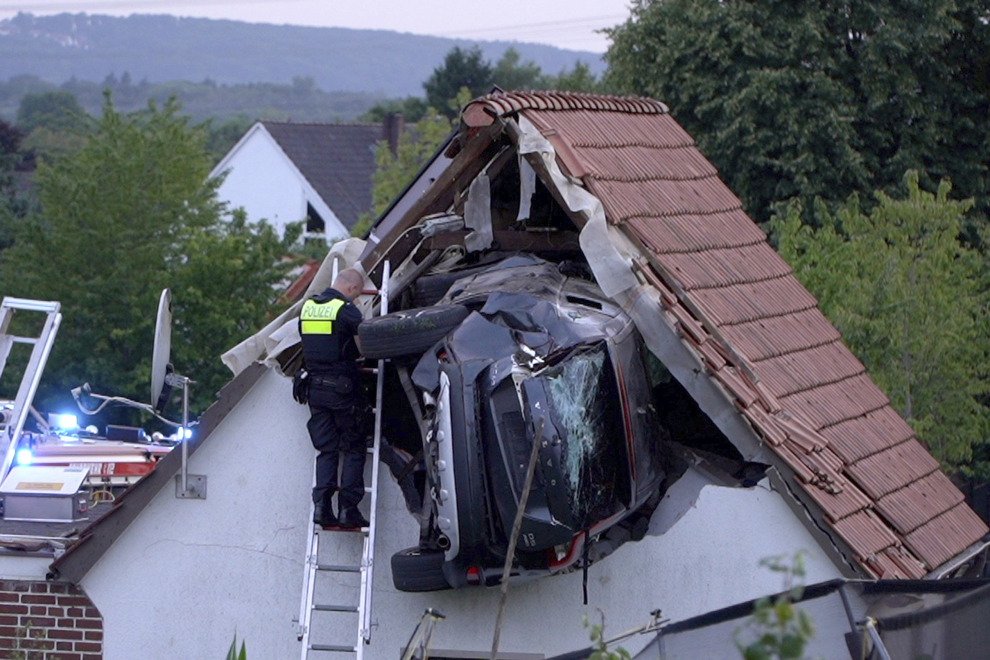 A police officer checks a car stuck in the wall of a barn following an accident in Bohmte, Germany, Sunday, July 20, 2025. (Torben Kipp/Nordwestmedia-TV/dpa via AP)