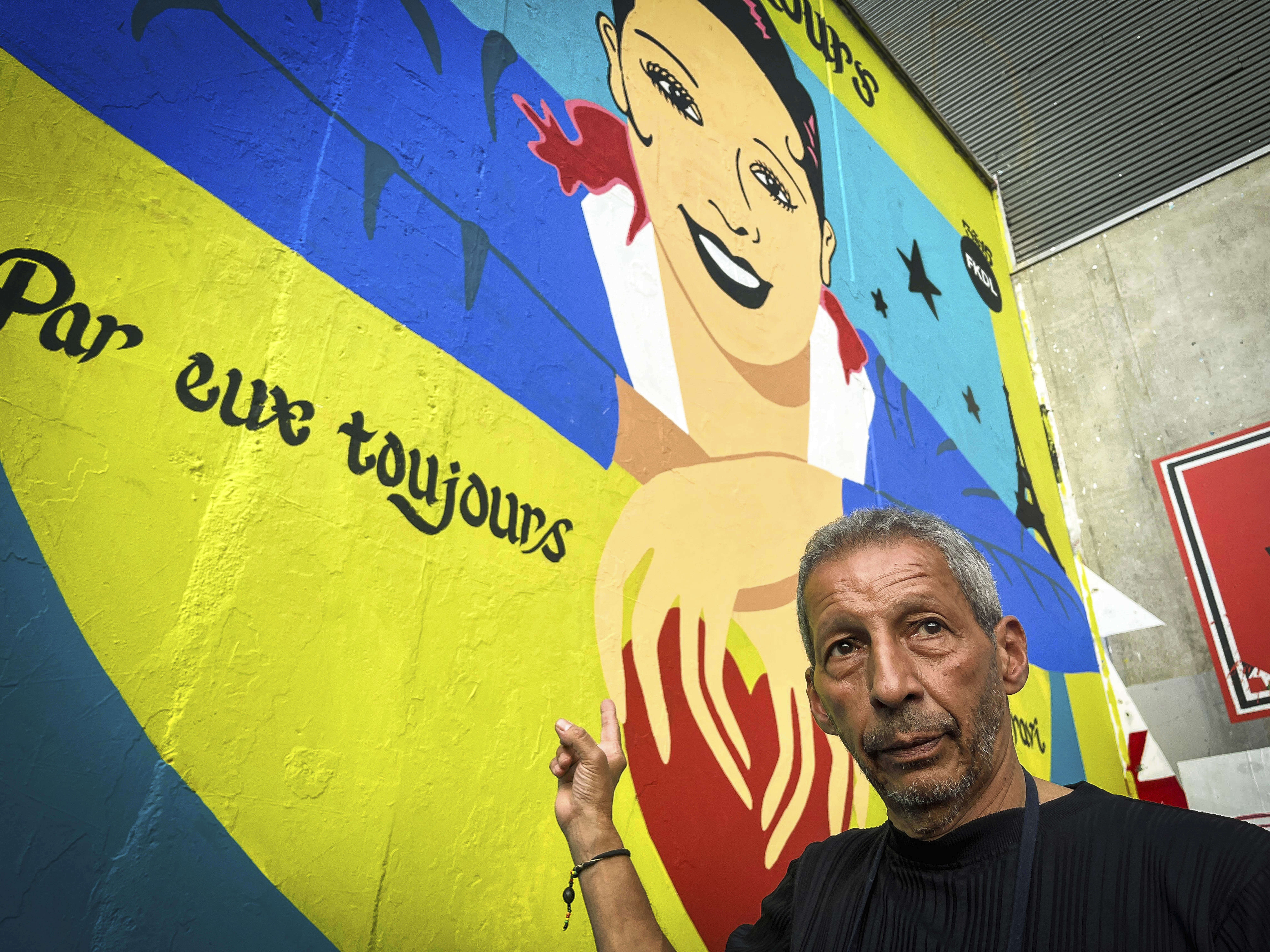 Brian Baker, son of U.S.-French entertainer and civil rights activist Josephine Baker, stands in front of a new mural of his mother painted by artist Franck Duval, aka FKDL, in Paris, Saturday, July 19, 2025. (AP Photo/Thomas Padilla)