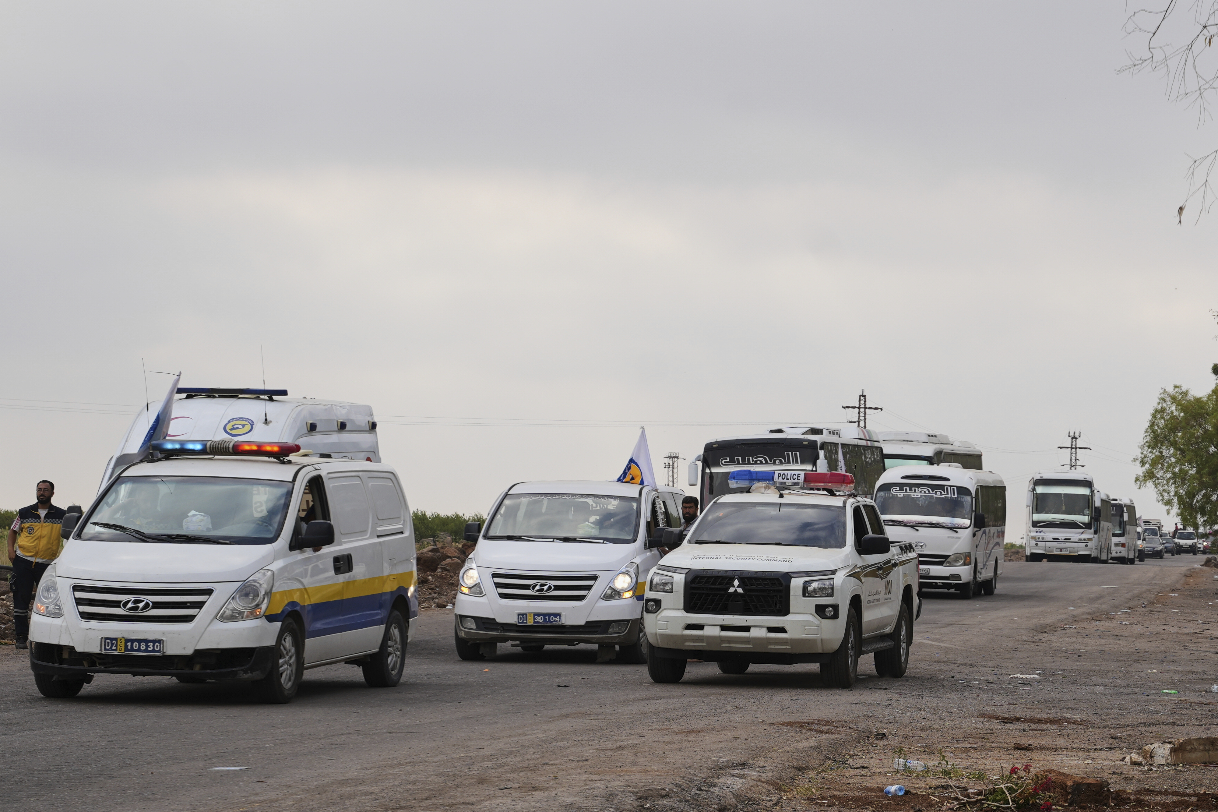 Syrian Bedouin families ride in a convoy led by Red Crescent vehicles in Busra al-Harir, heading to Daraa after being evacuated from Sweida following more than a week of violent clashes, Monday, July 21, 2025. (AP Photo/Malek Khattab)