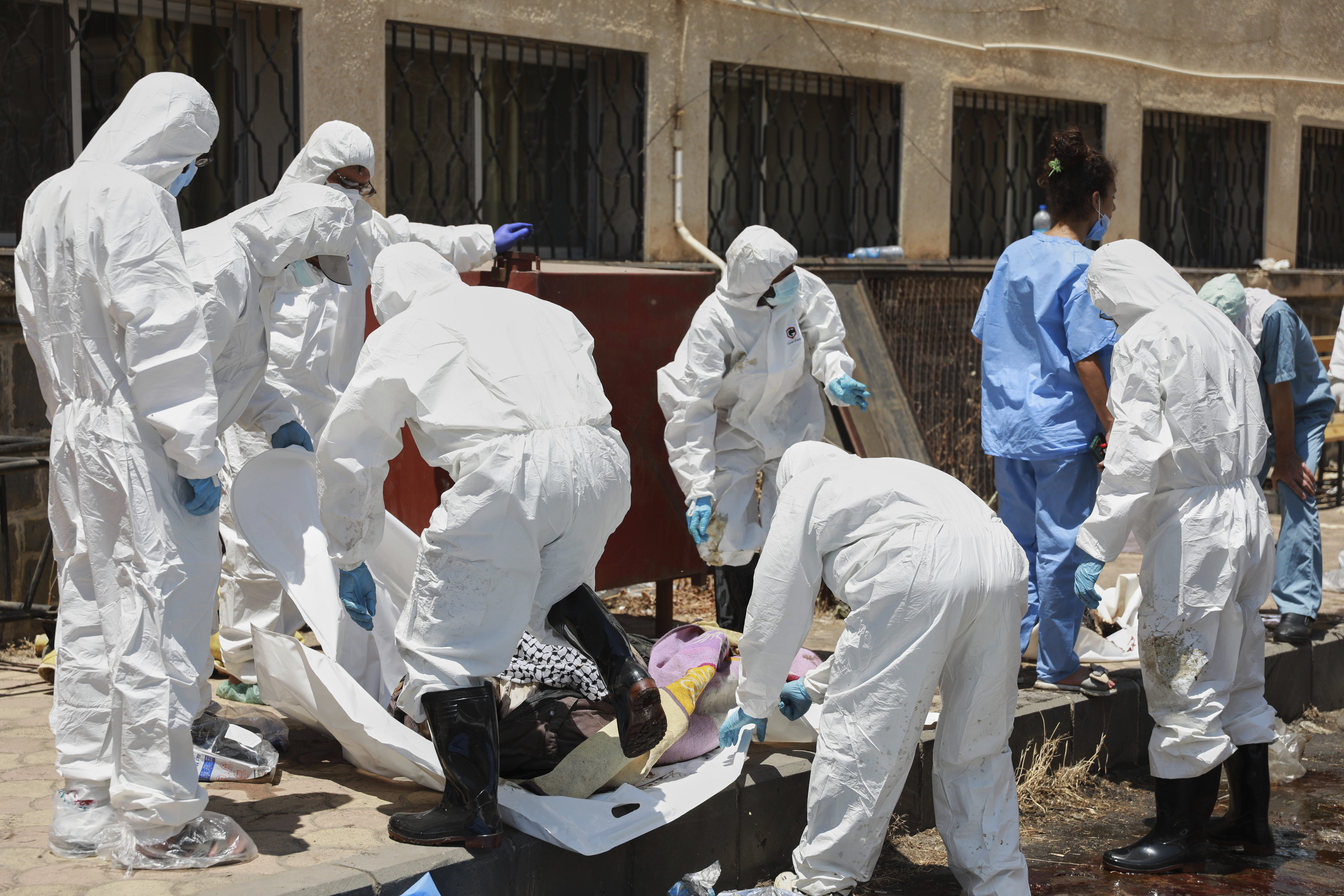 Morgue workers place the bodies of unidentified people killed during clashes between Bedouin clans and Druze militias, into plastic bags outside the National Hospital in Sweida, Syria, Monday, July 21, 2025. (AP Photo/Fahd Kiwan)