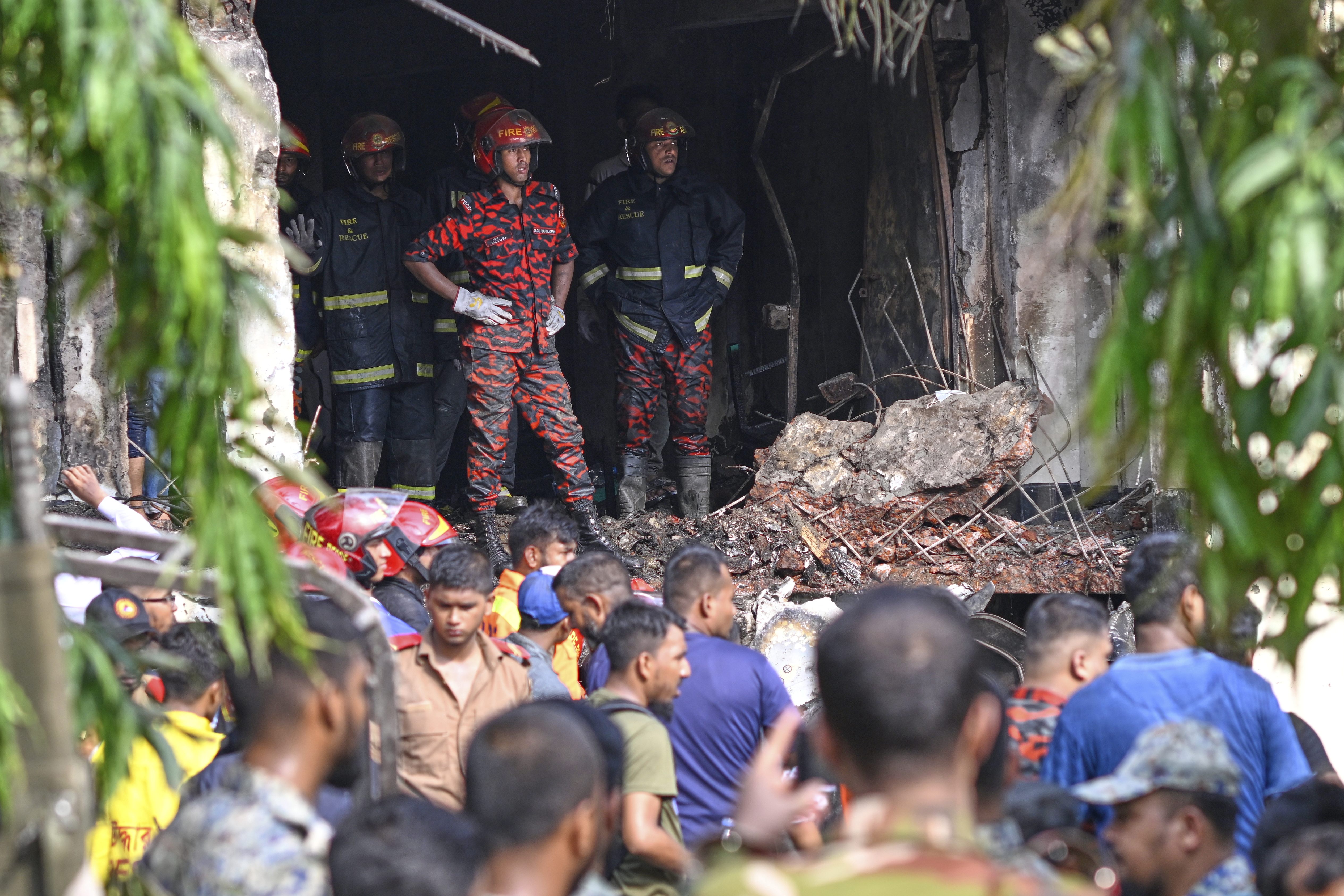 Firemen look for the survivors after a Bangladesh Air Force training aircraft that crashed onto a school campus shortly after takeoff in Dhaka, Bangladesh, Monday, July 21, 2025. (AP Photo/Mahmud Hossain Opu)