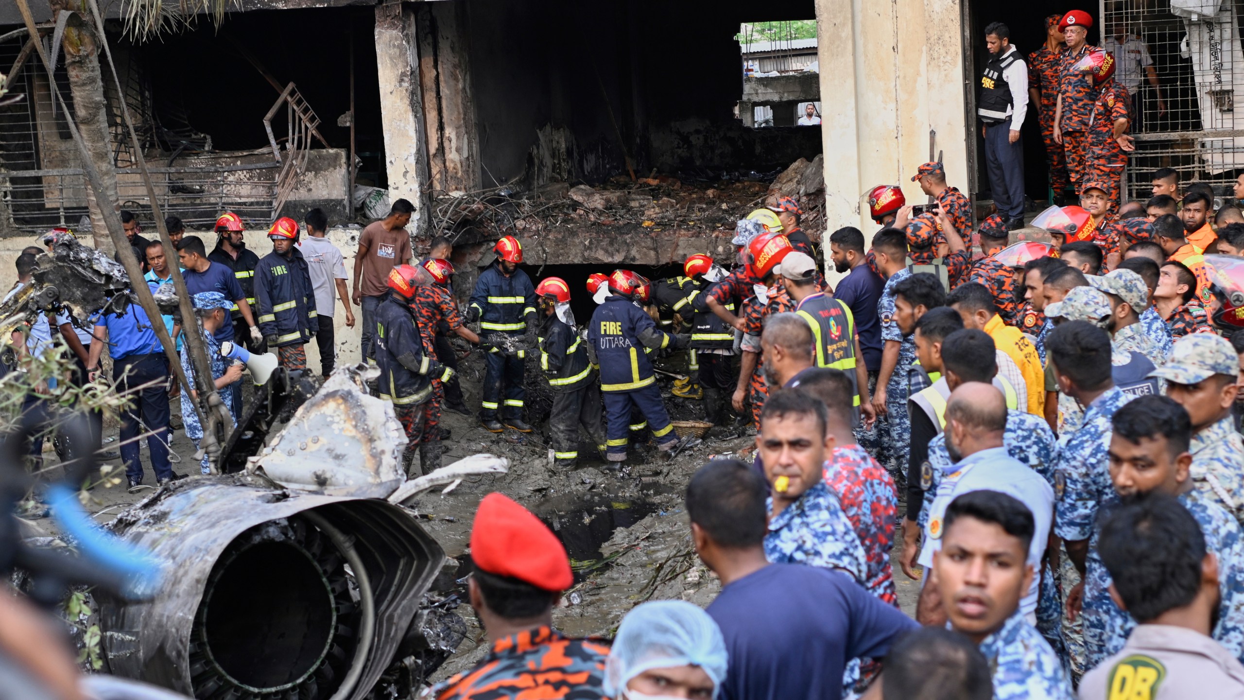 Firemen look for the survivors after a Bangladesh Air Force training aircraft that crashed onto a school campus shortly after takeoff in Dhaka, Bangladesh, Monday, July 21, 2025. (AP Photo/Mahmud Hossain Opu)