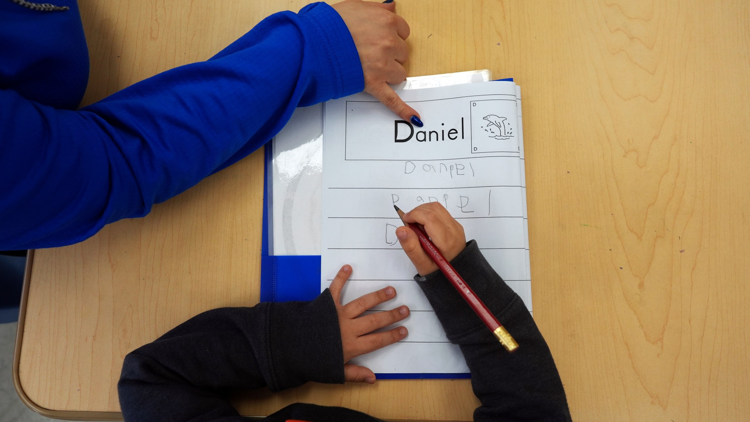 FILE - Easterseals Head Start program teaching assistant Tania Ortiz helps a student practice writing his name, Jan. 29, 2025, in Miami. (AP Photo/Rebecca Blackwell, File)