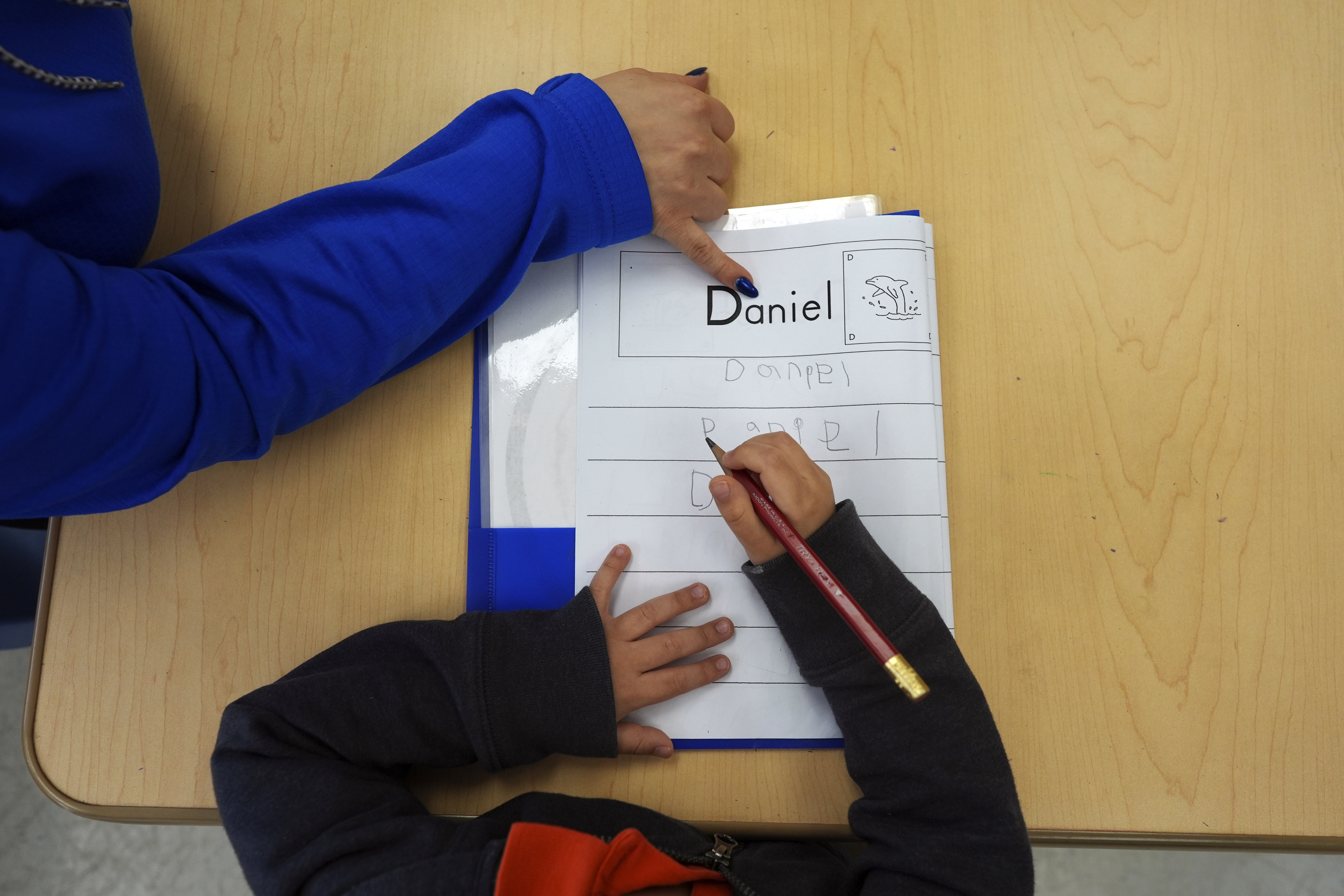 FILE - Easterseals Head Start program teaching assistant Tania Ortiz helps a student practice writing his name, Jan. 29, 2025, in Miami. (AP Photo/Rebecca Blackwell, File)