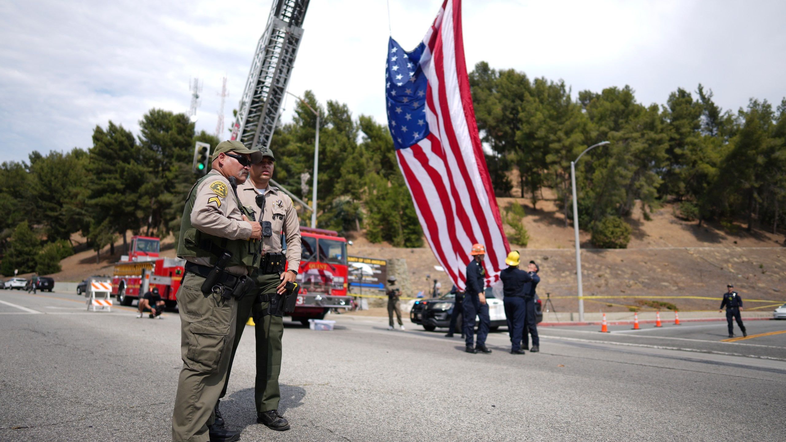 Sheriff's deputies stand along a procession route near where an explosion at a training facility killed three deputies on Friday, July 18, 2025, in Los Angeles. (AP Photo/Eric Thayer)