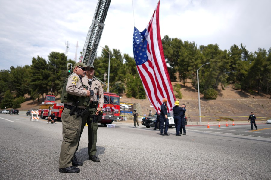Sheriff's deputies stand along a procession route near where an explosion at a training facility killed three deputies on Friday, July 18, 2025, in Los Angeles. (AP Photo/Eric Thayer)