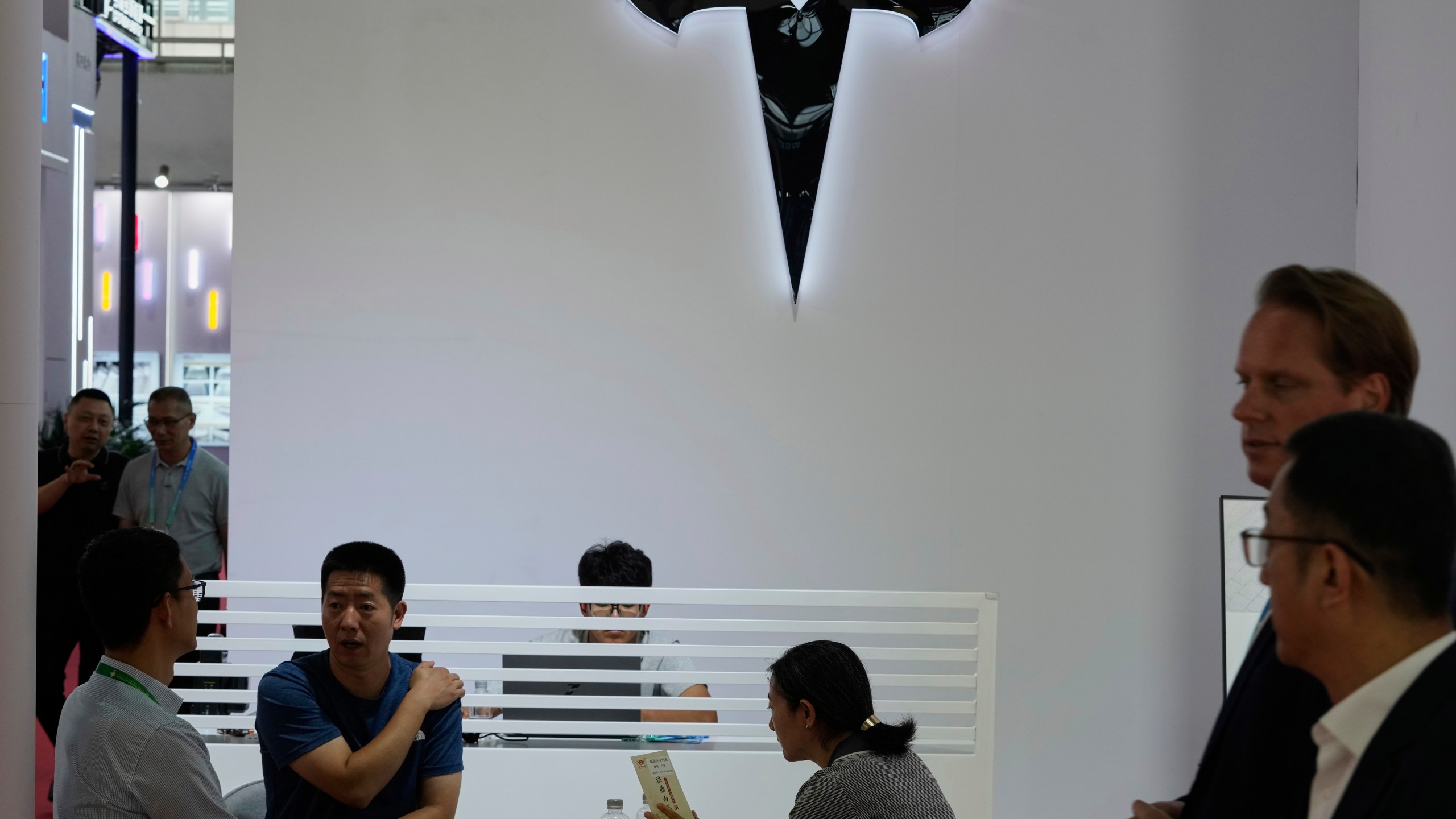 Visitors at the Tesla booth during the 3rd China International Supply Chain Expo at the China International Exhibition Center, in Beijing, China, Friday, July 18, 2025. (AP Photo/Mahesh Kumar A.)