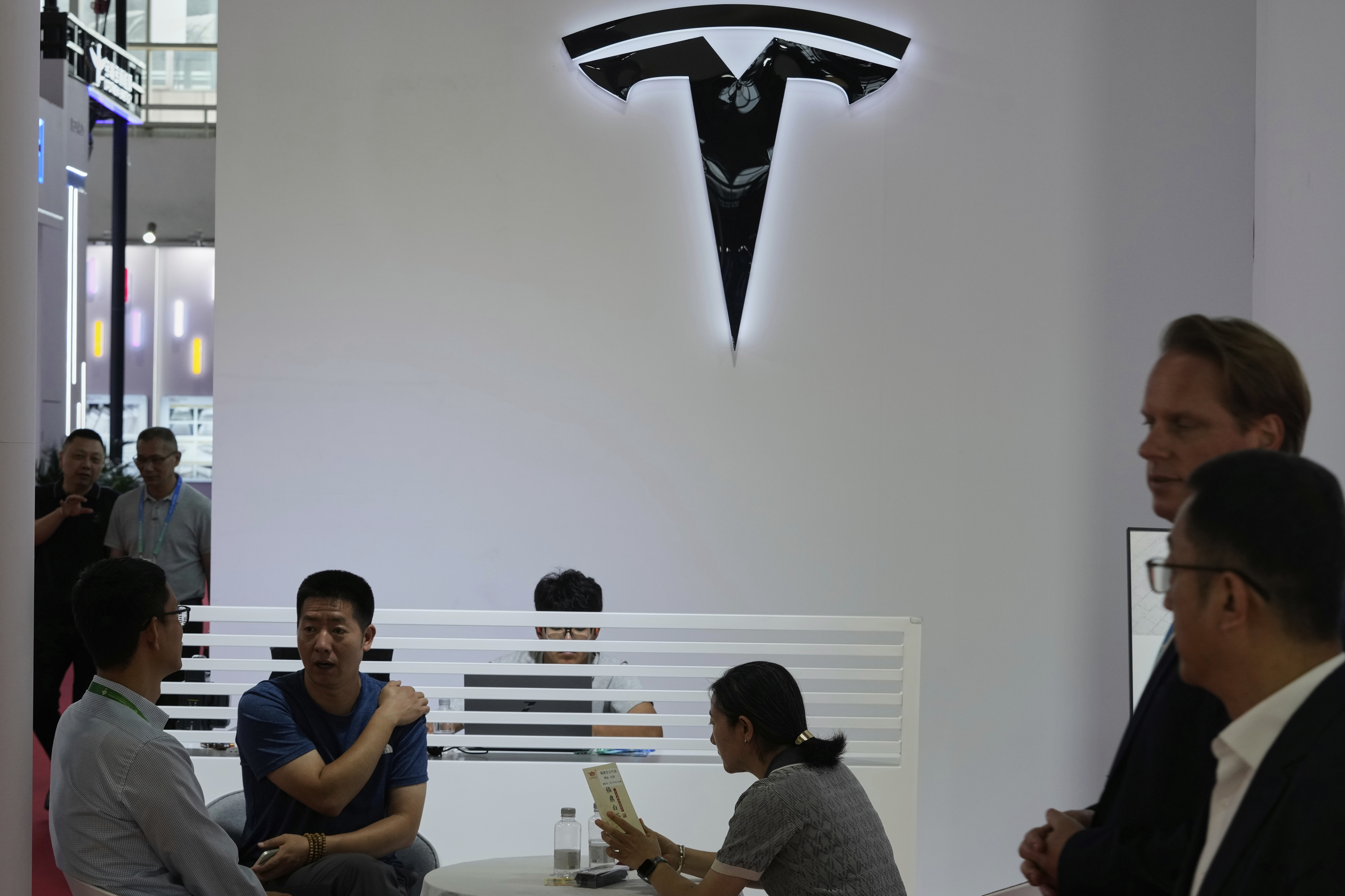 Visitors at the Tesla booth during the 3rd China International Supply Chain Expo at the China International Exhibition Center, in Beijing, China, Friday, July 18, 2025. (AP Photo/Mahesh Kumar A.)